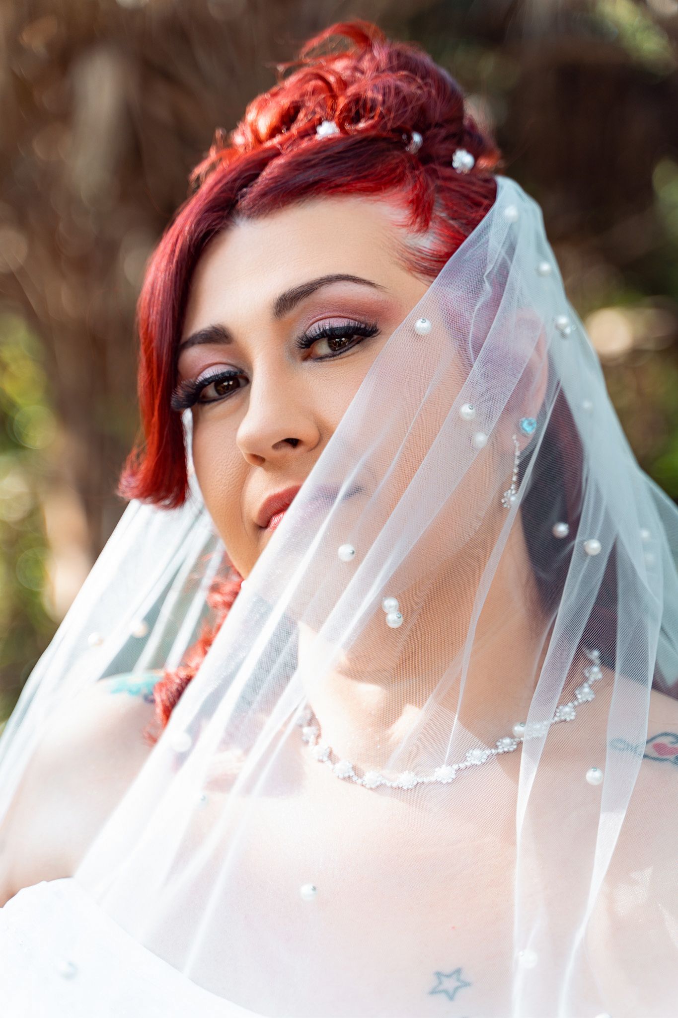 Close up of a bride with red hair wearing a delicate pearl-studded veil.