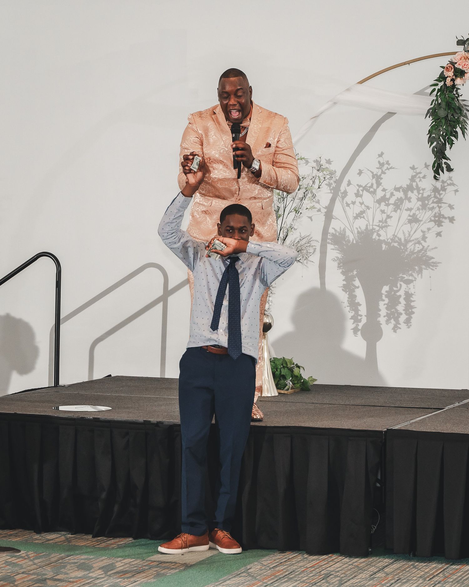 Fun wedding reception moment captured on stage with energetic poses.