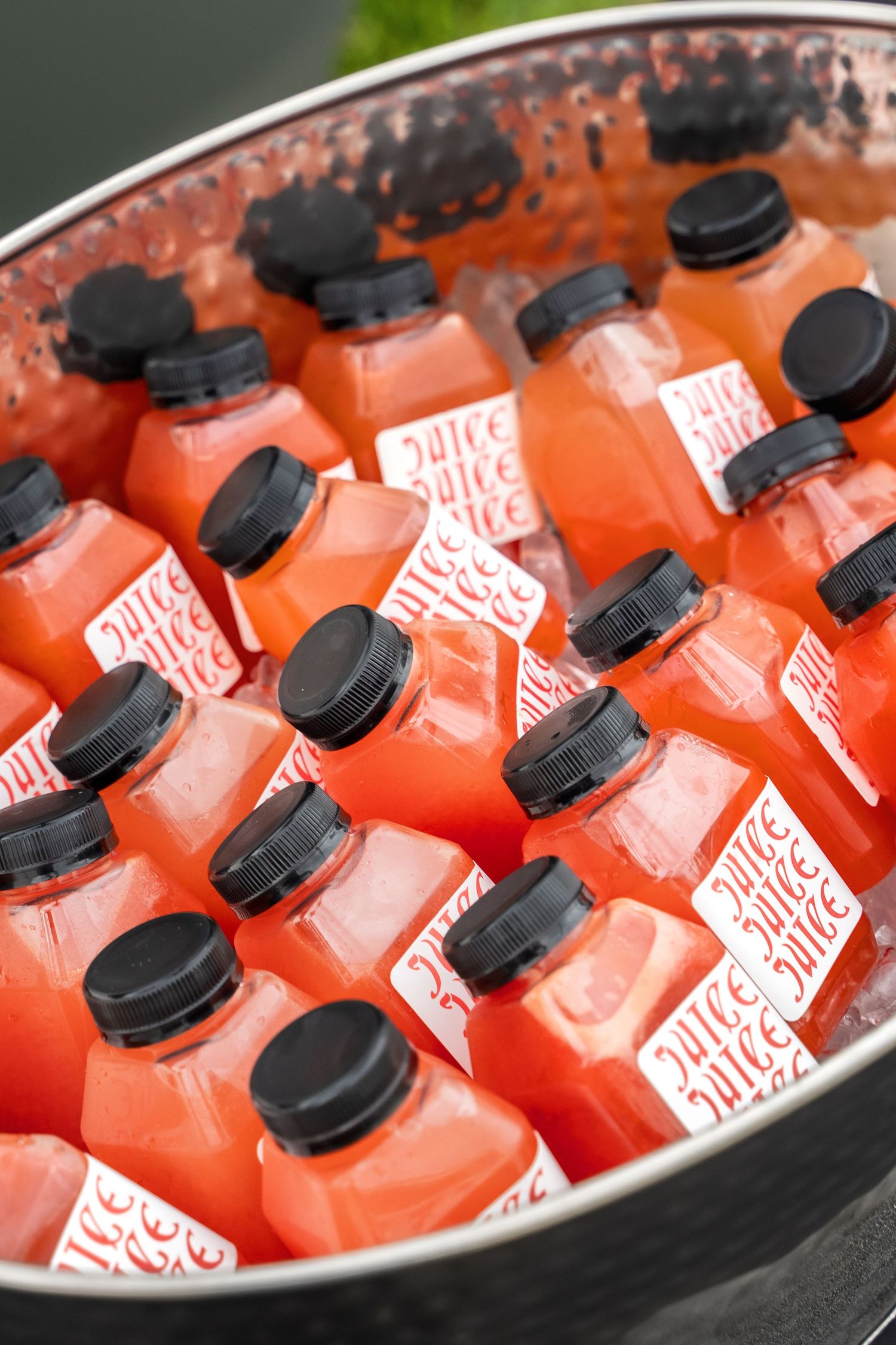 Orange bottled beverages chilling in metal tub filled with ice.