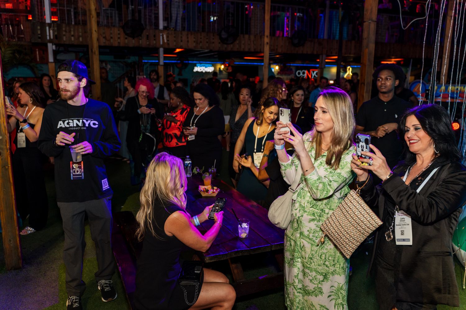 Nightclub crowd enjoying entertainment with smartphones raised in dimly lit venue.