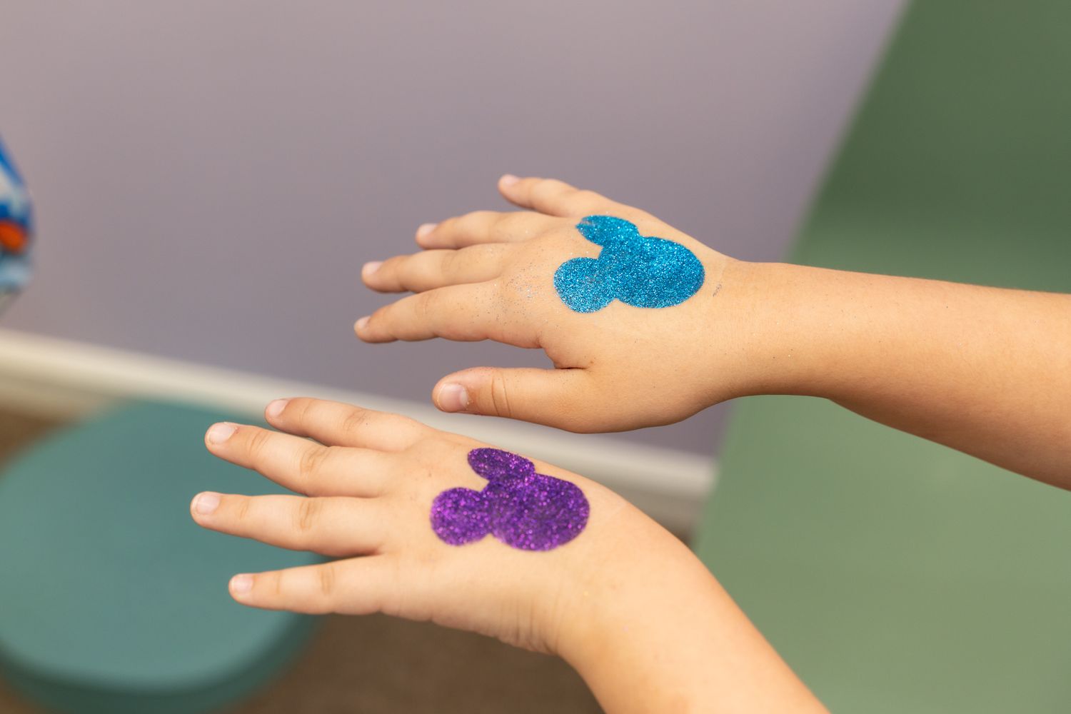 Two hands displaying blue and purple Mickey Mouse designs painted on them.