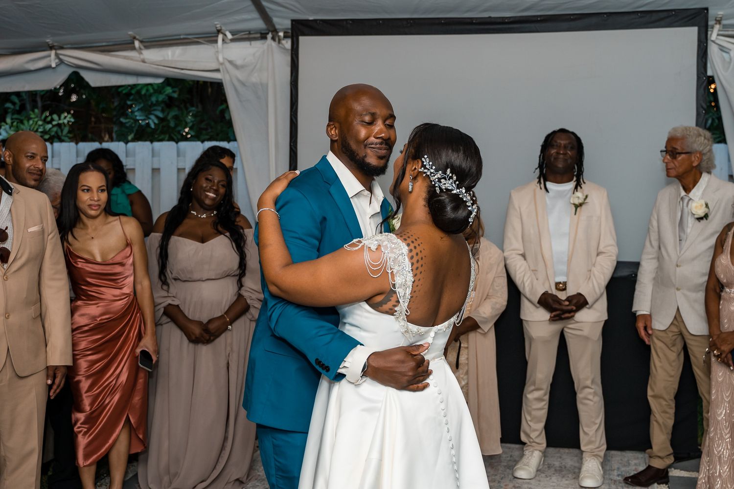 Wedding couple dances while guests in pink and beige dresses watch from the sidelines.
