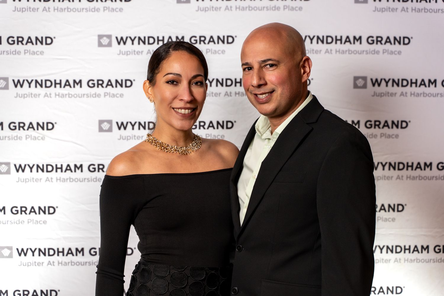 Couple posing for a photo against a Wyndham Grand backdrop at an event.