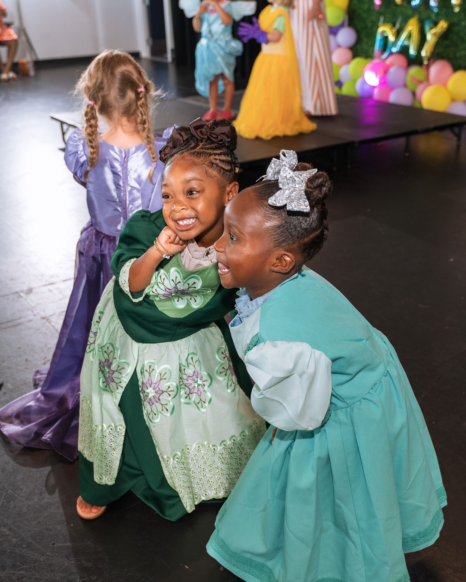 Children in fancy dress costumes having fun at a party with balloon decorations.