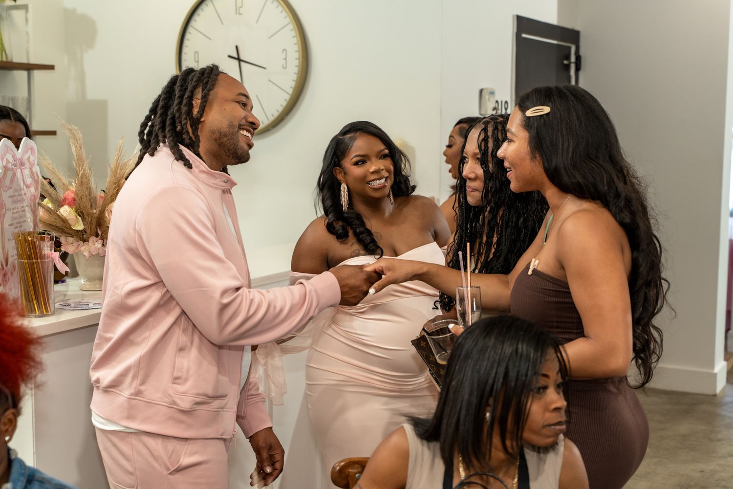 Guests mingling and socializing at an indoor celebration with pink decor elements.