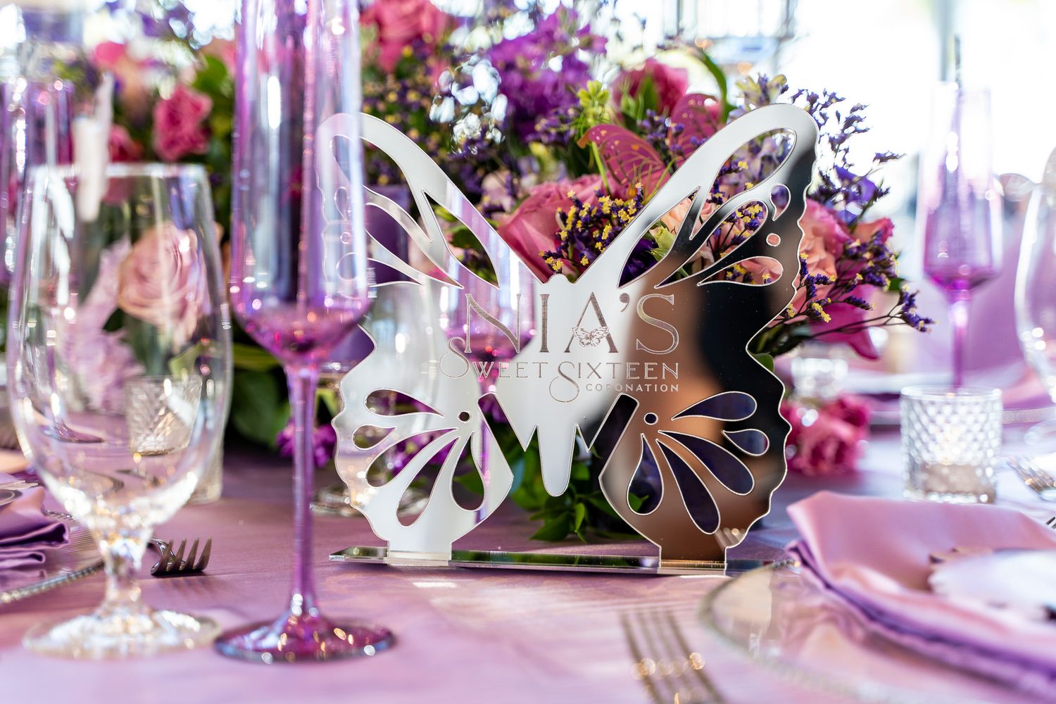 Elegant table setting with metallic butterfly decorations and purple glassware.