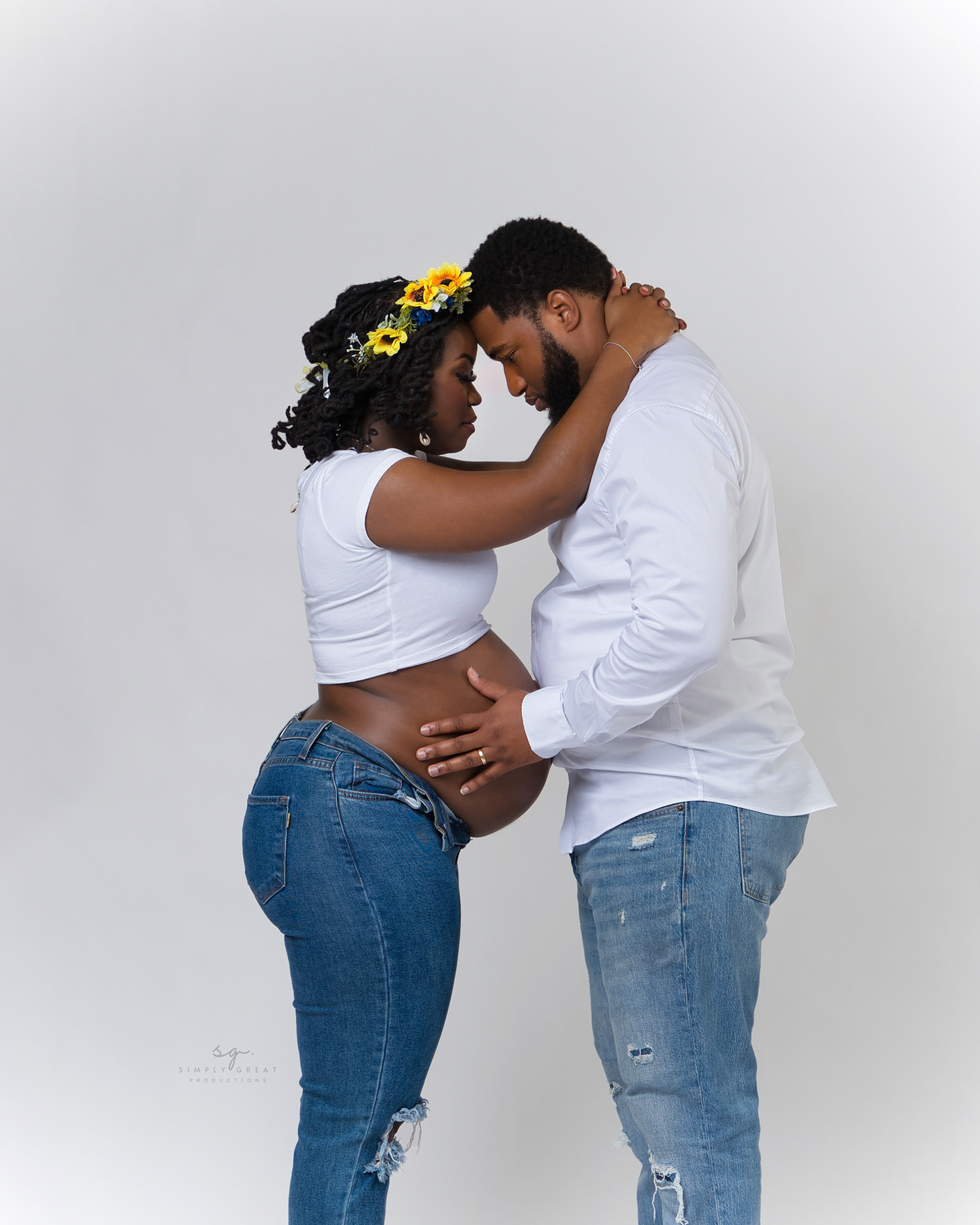 Intimate maternity portrait of couple in casual attire sharing tender moment.