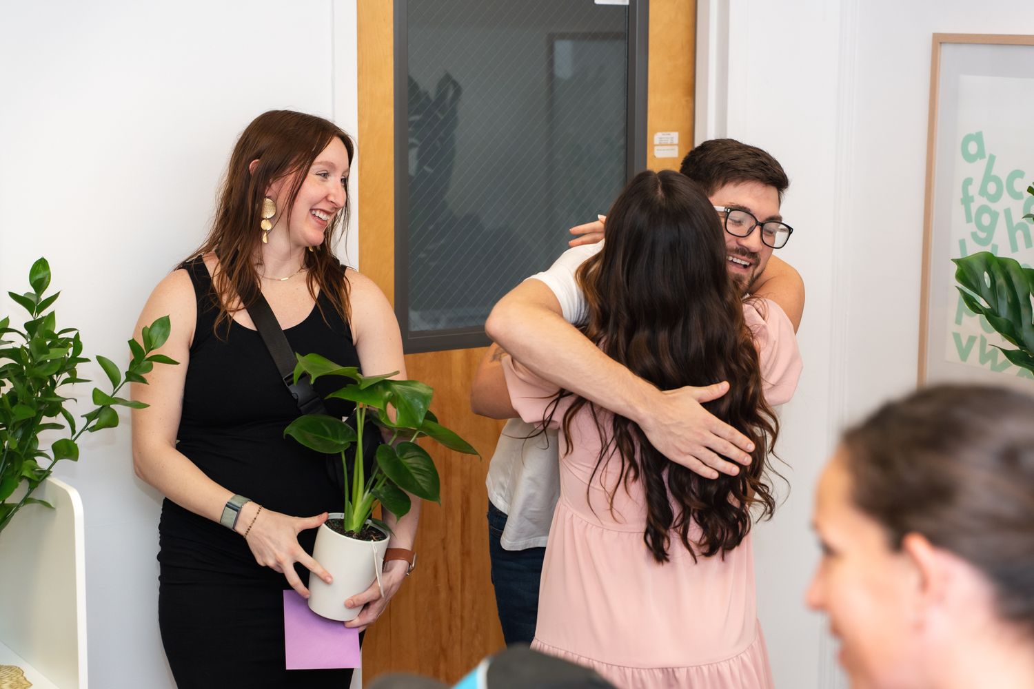 People sharing joyful moment with plants and hugs in bright indoor setting.