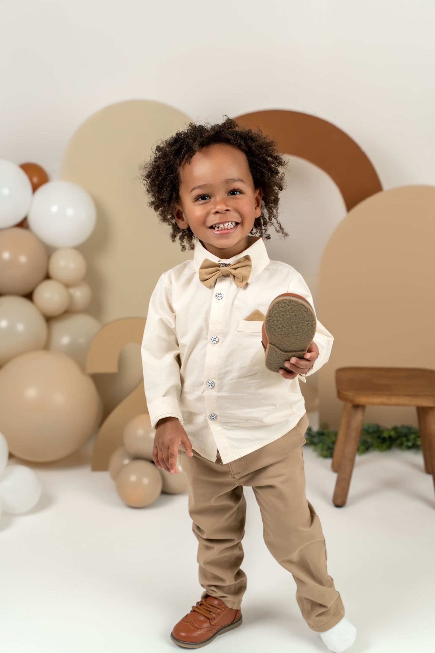 A series of photos showing a toddler in a white sweater and tan pants posing against a neutral backdrop with balloons.