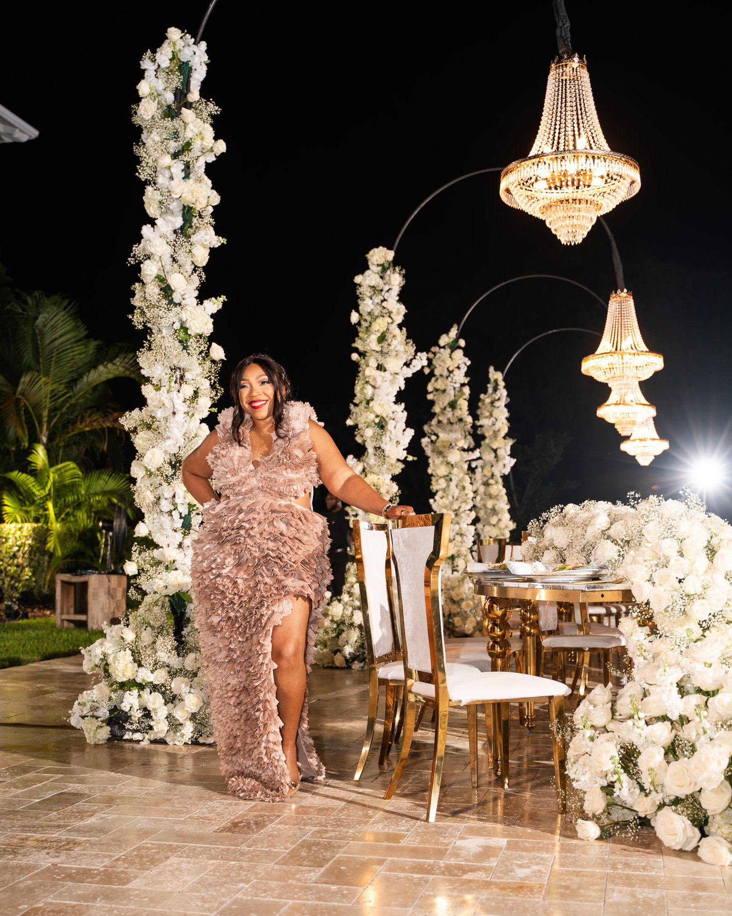 Luxurious event space decorated with white floral columns and crystal chandeliers.