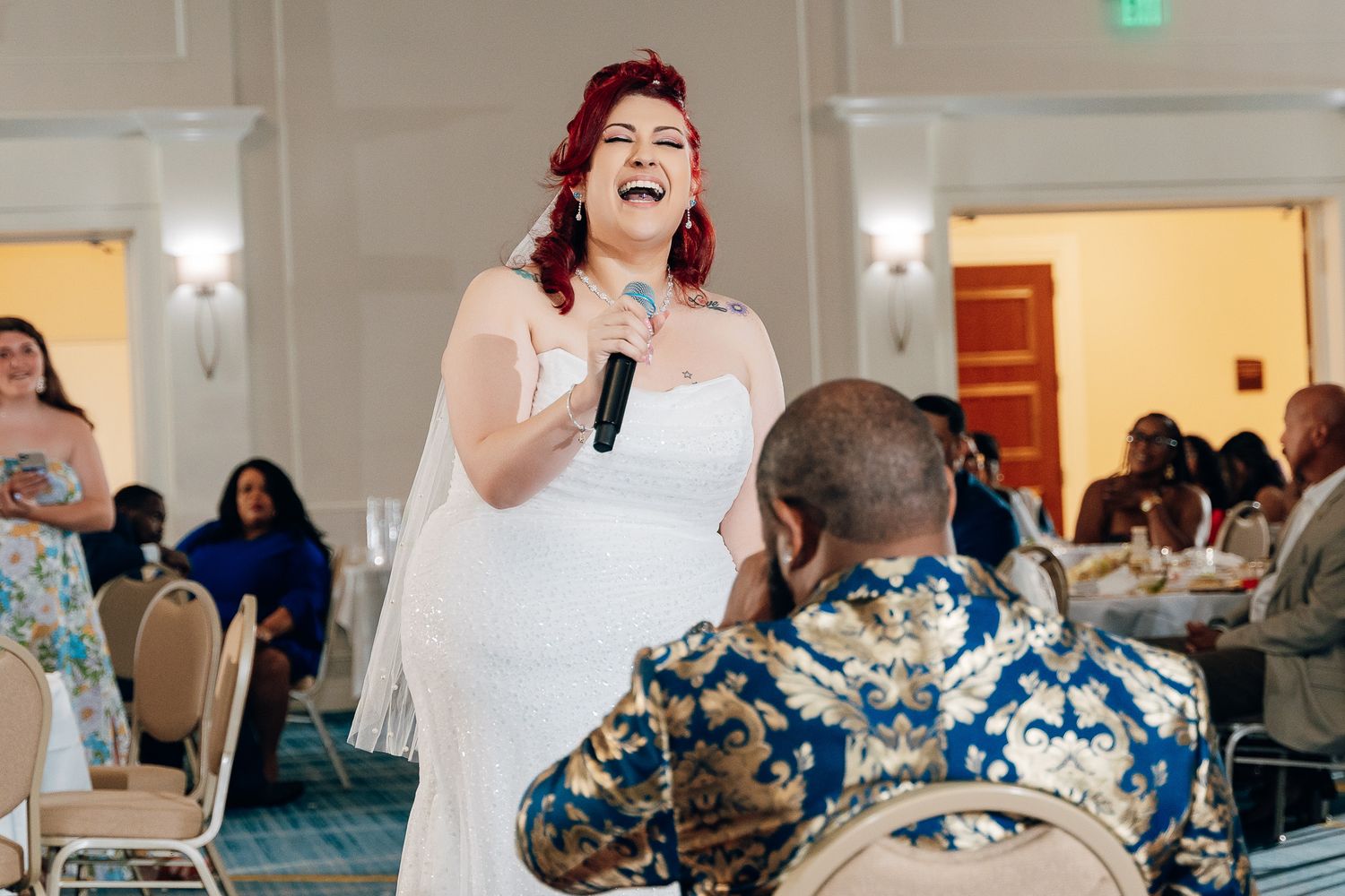 A bride in a white dress sings with a microphone during her wedding reception.