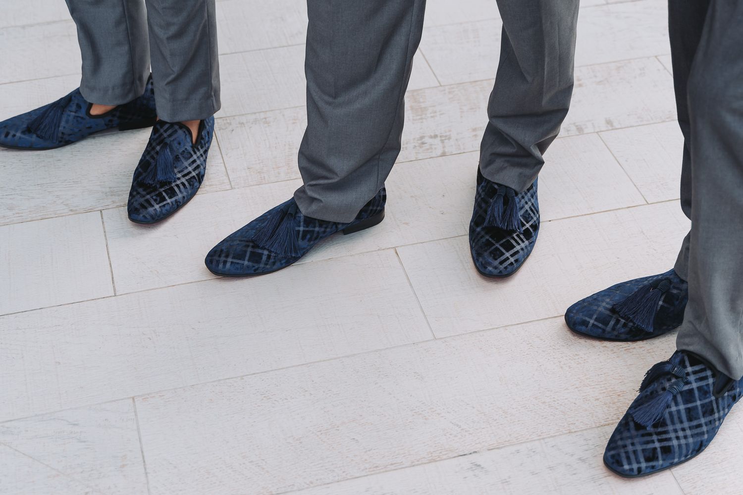 Row of groomsmen's feet wearing matching navy blue dress shoes.