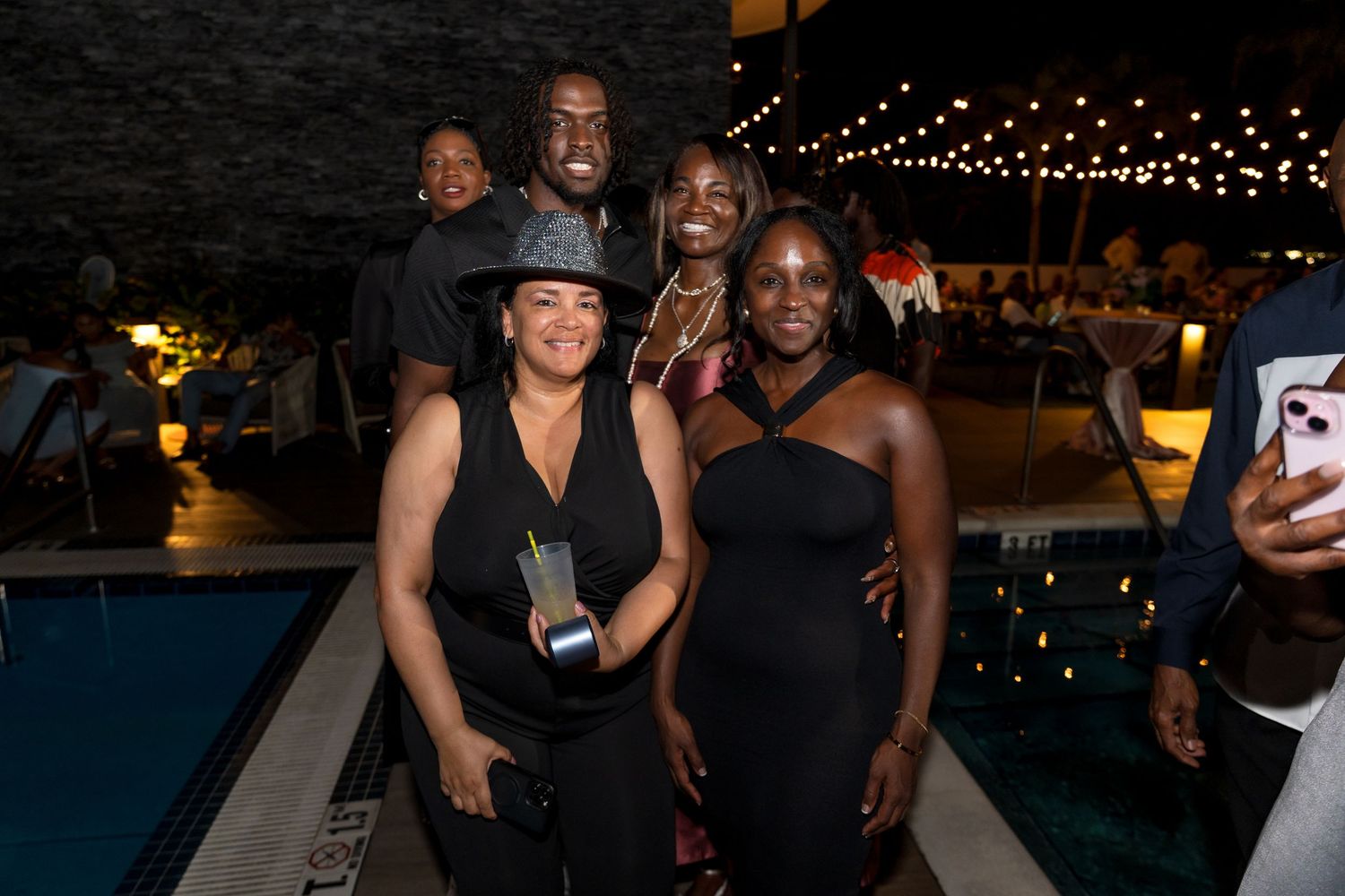 Group posing together at nighttime event with string lights visible in background.