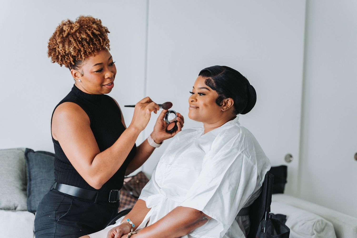 Makeup artist applying cosmetics with brushes during a bridal beauty session.