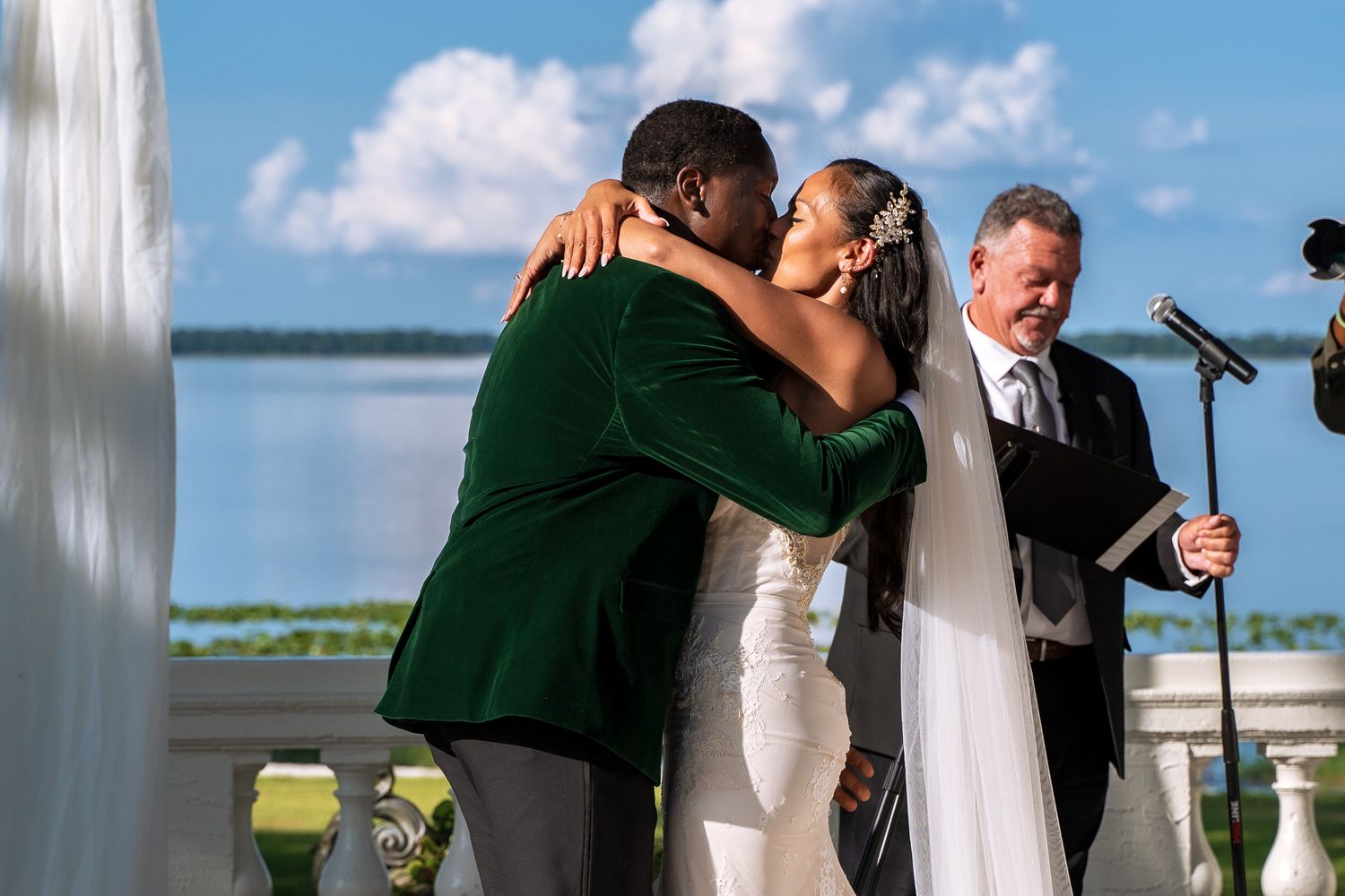 Newlyweds share their first kiss during waterfront wedding ceremony.