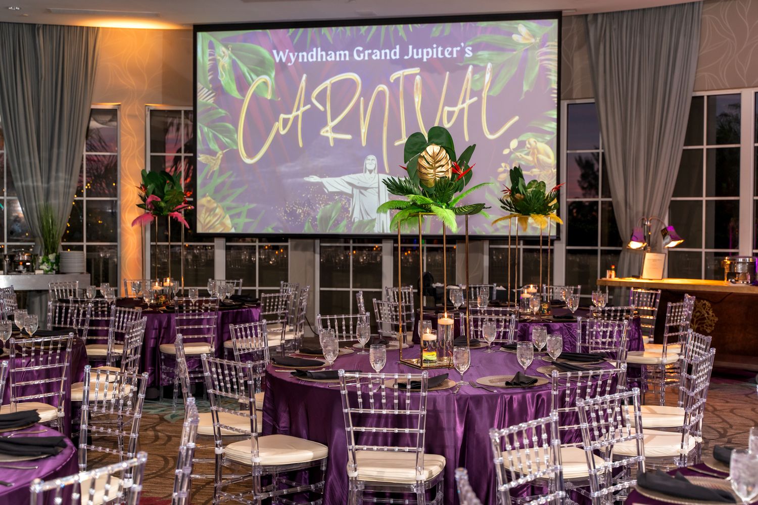An elegant ballroom setup with purple decor and a carnival-themed projection display.