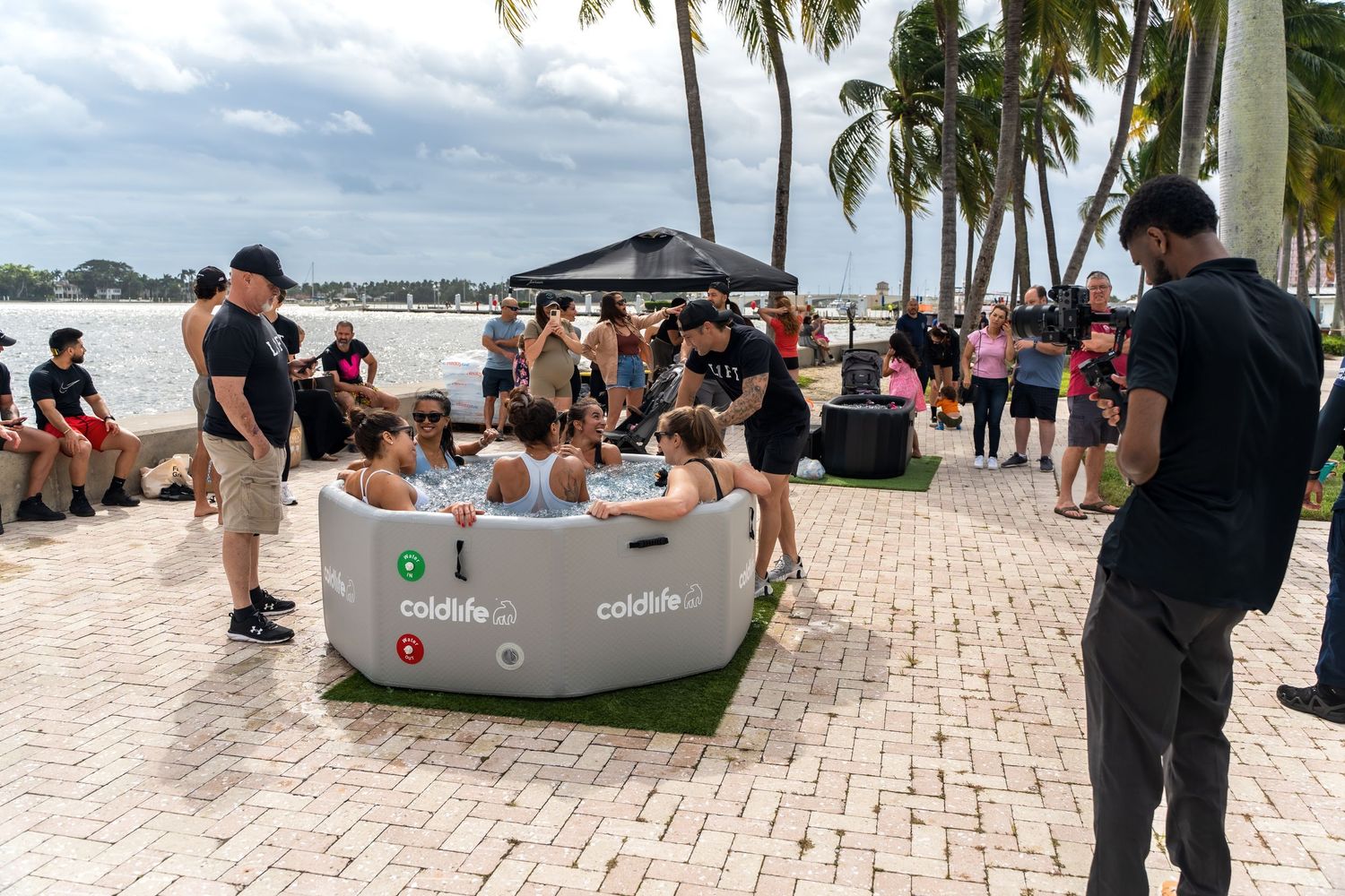 Outdoor spa event with inflatable pools and participants gathering on a waterfront patio.