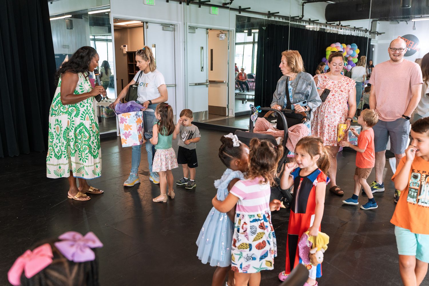 Groups of families and children mingle in a spacious studio during a special event.
