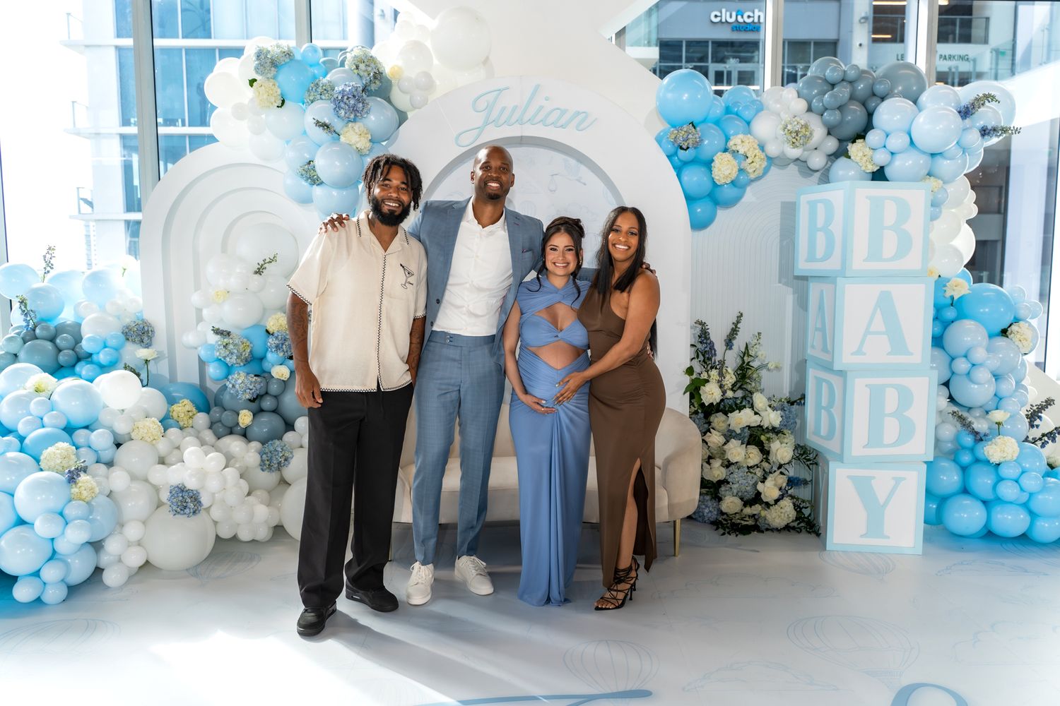 Family group photo against a decorative backdrop with blue and white balloons.