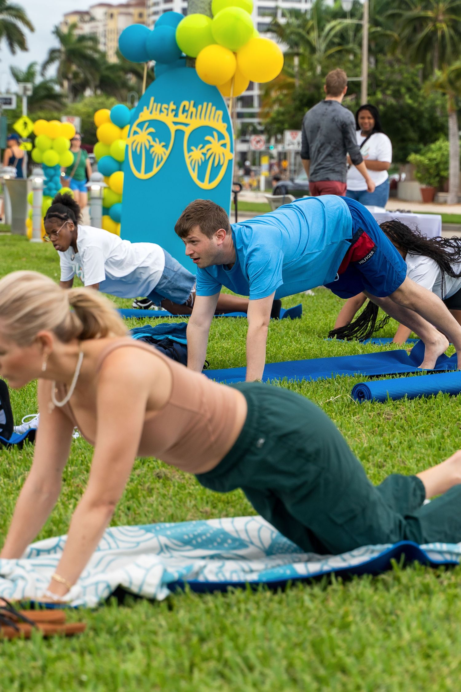 People doing plank exercises on yoga mats at outdoor fitness event with colorful balloons.