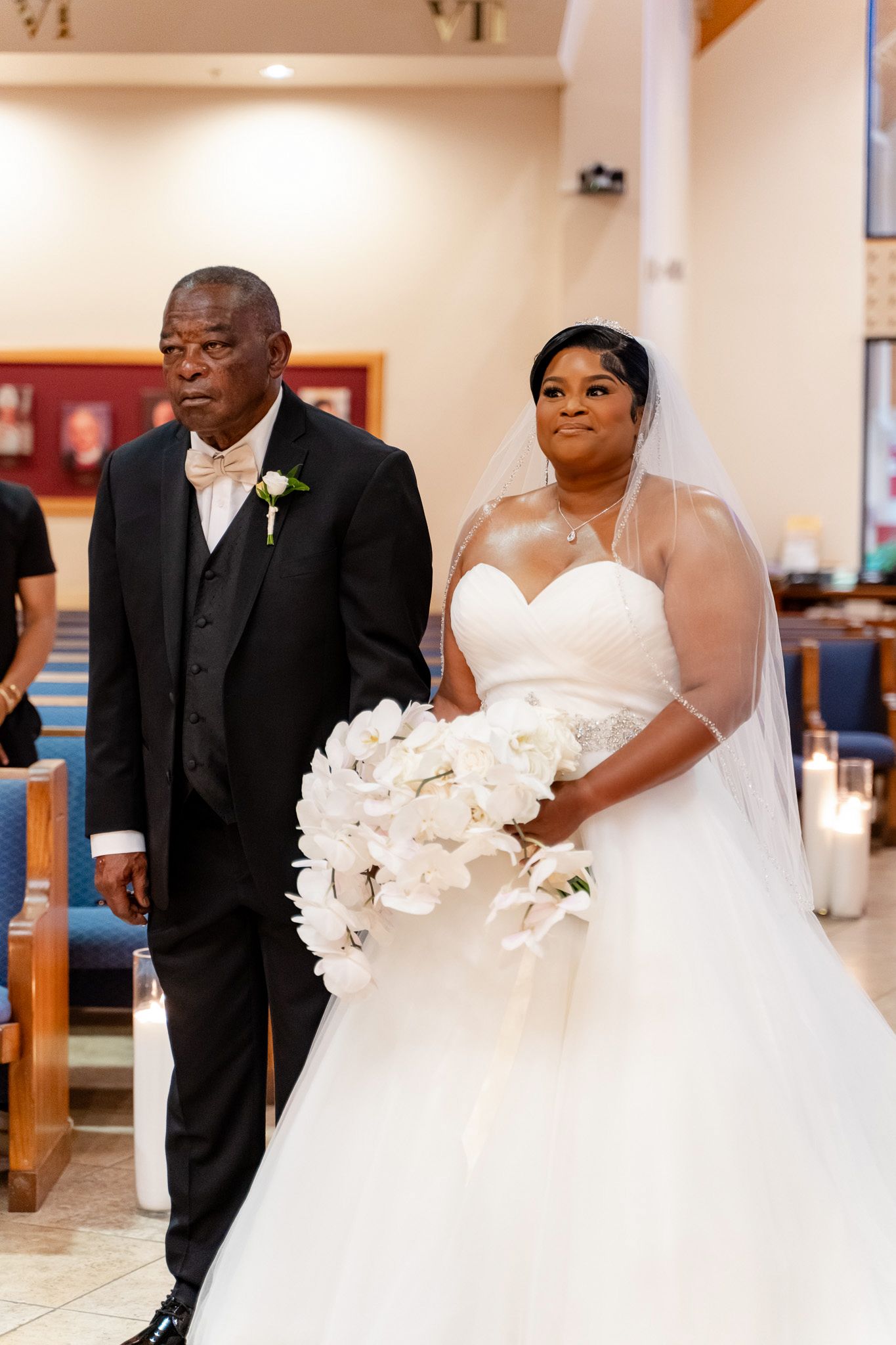 Bride in white sweetheart gown holding bouquet standing in church ceremony.