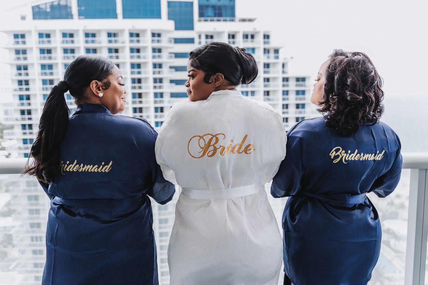 Three robes showing 'Bridesmaid', 'Bride', and 'Bridesmaid' text in gold embroidery.