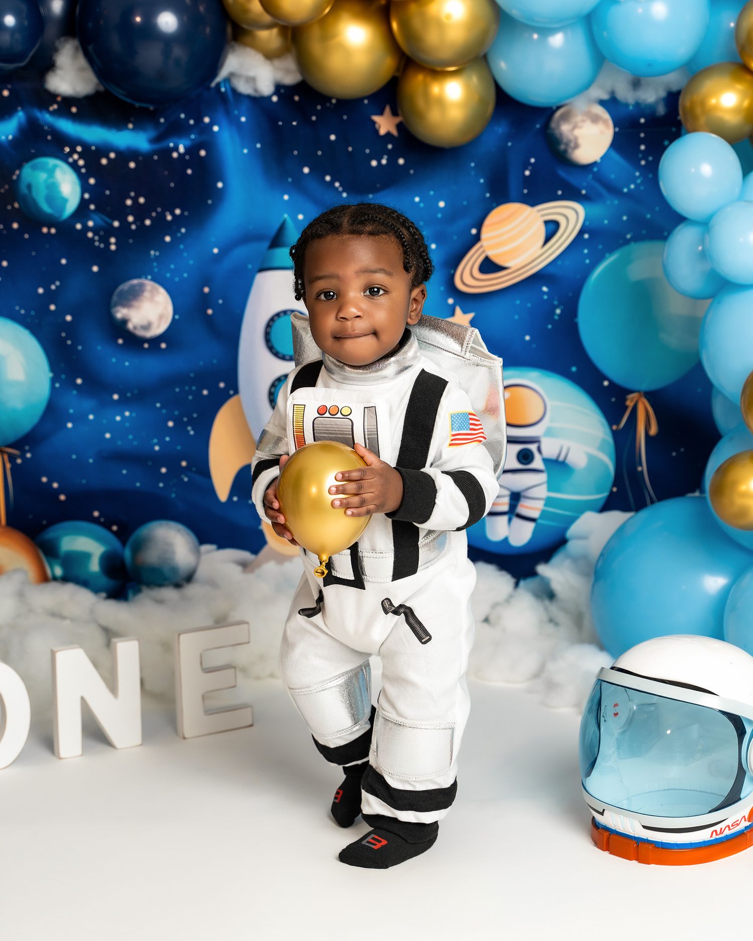 Space-themed birthday setup with balloons, planets, and astronaut decorations against a starry background.