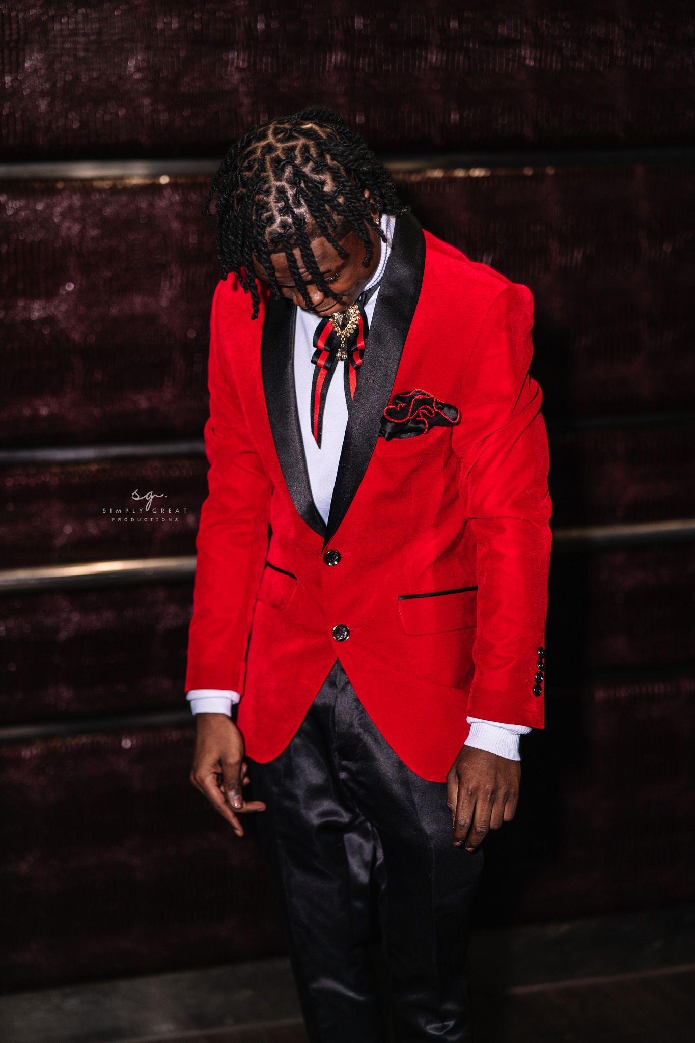 Fashion portrait featuring red blazer against dark textured background.