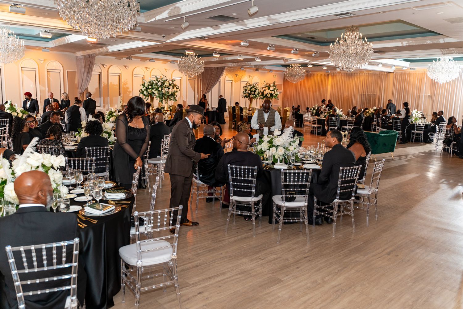 A spacious wedding reception ballroom with crystal chandeliers and elegant table settings.