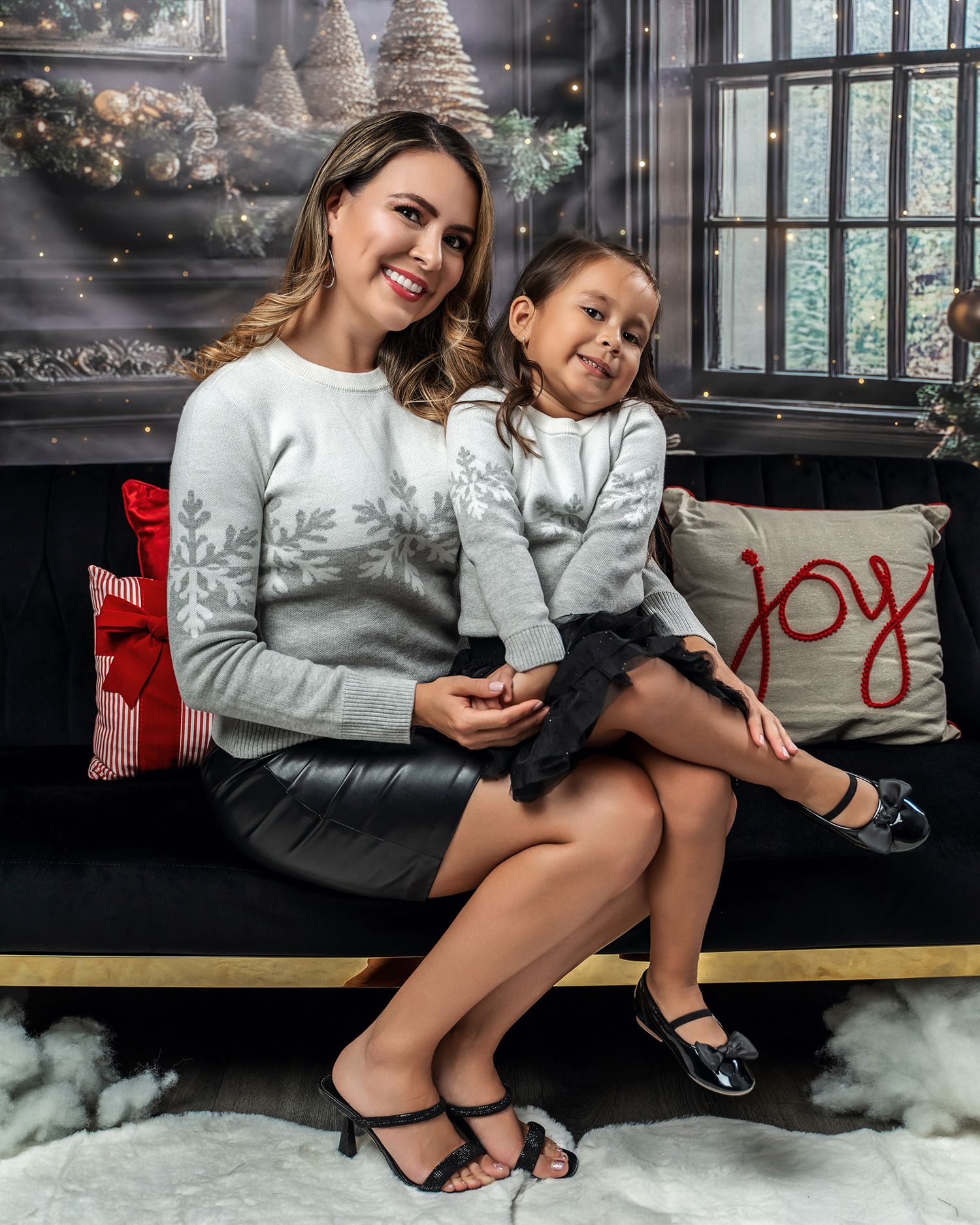 A cozy holiday scene with matching white sweaters on a bench with decorative pillows and Christmas decor.