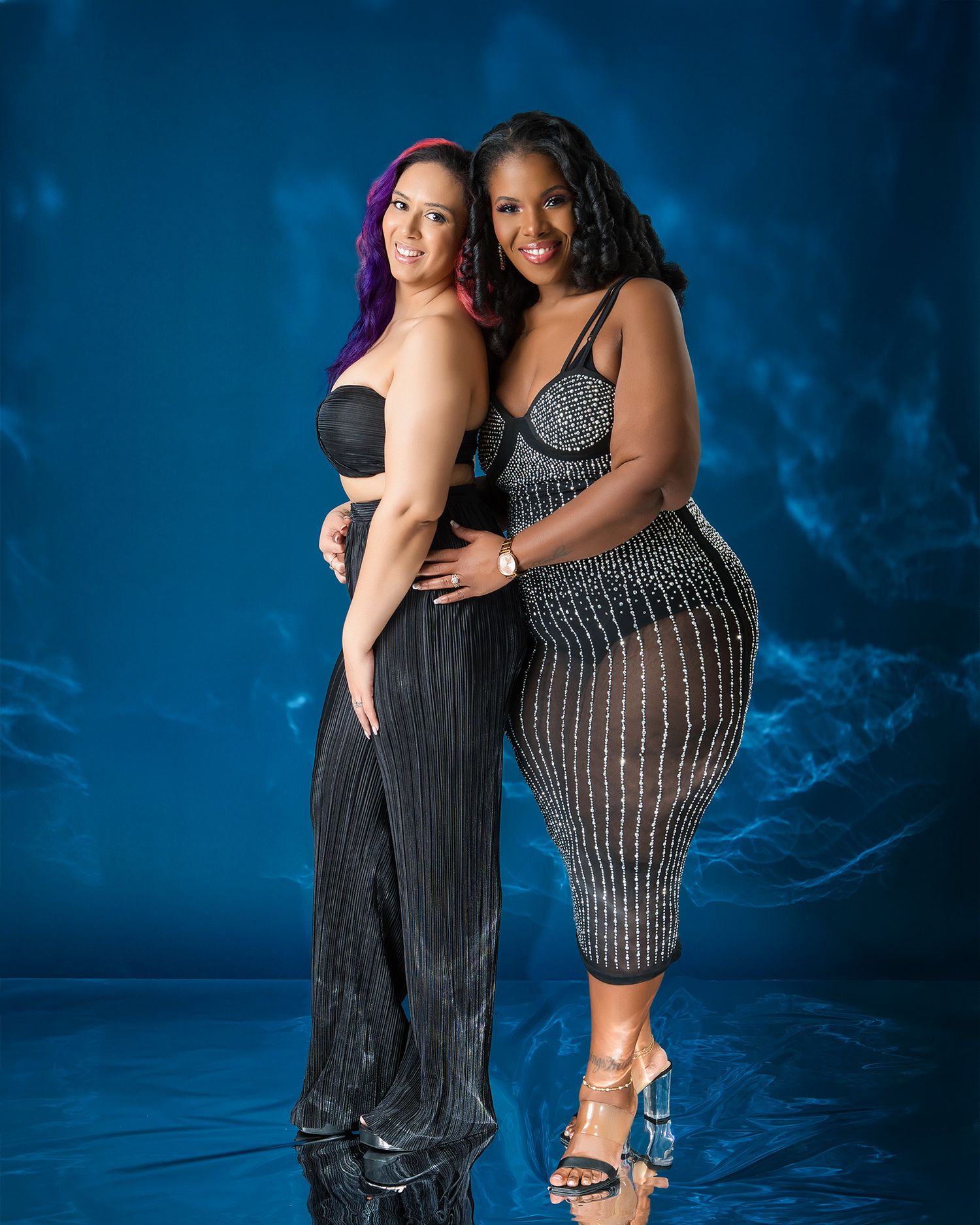 Models showcasing elegant black dresses pose together in a professional studio setting.