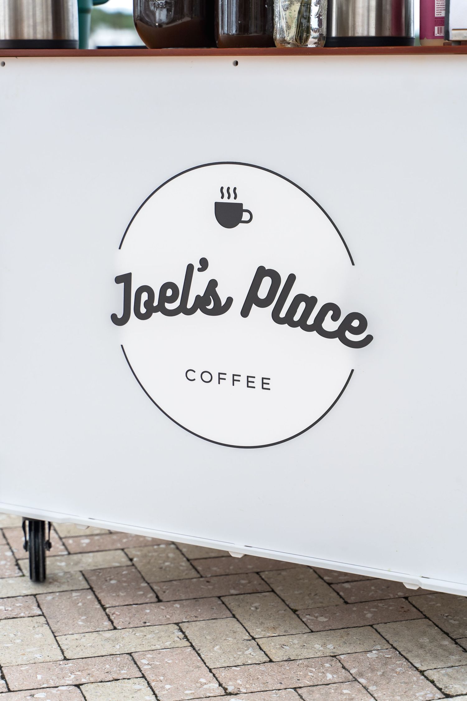 Joel's Place Coffee logo displayed on a white wall with minimalist design.
