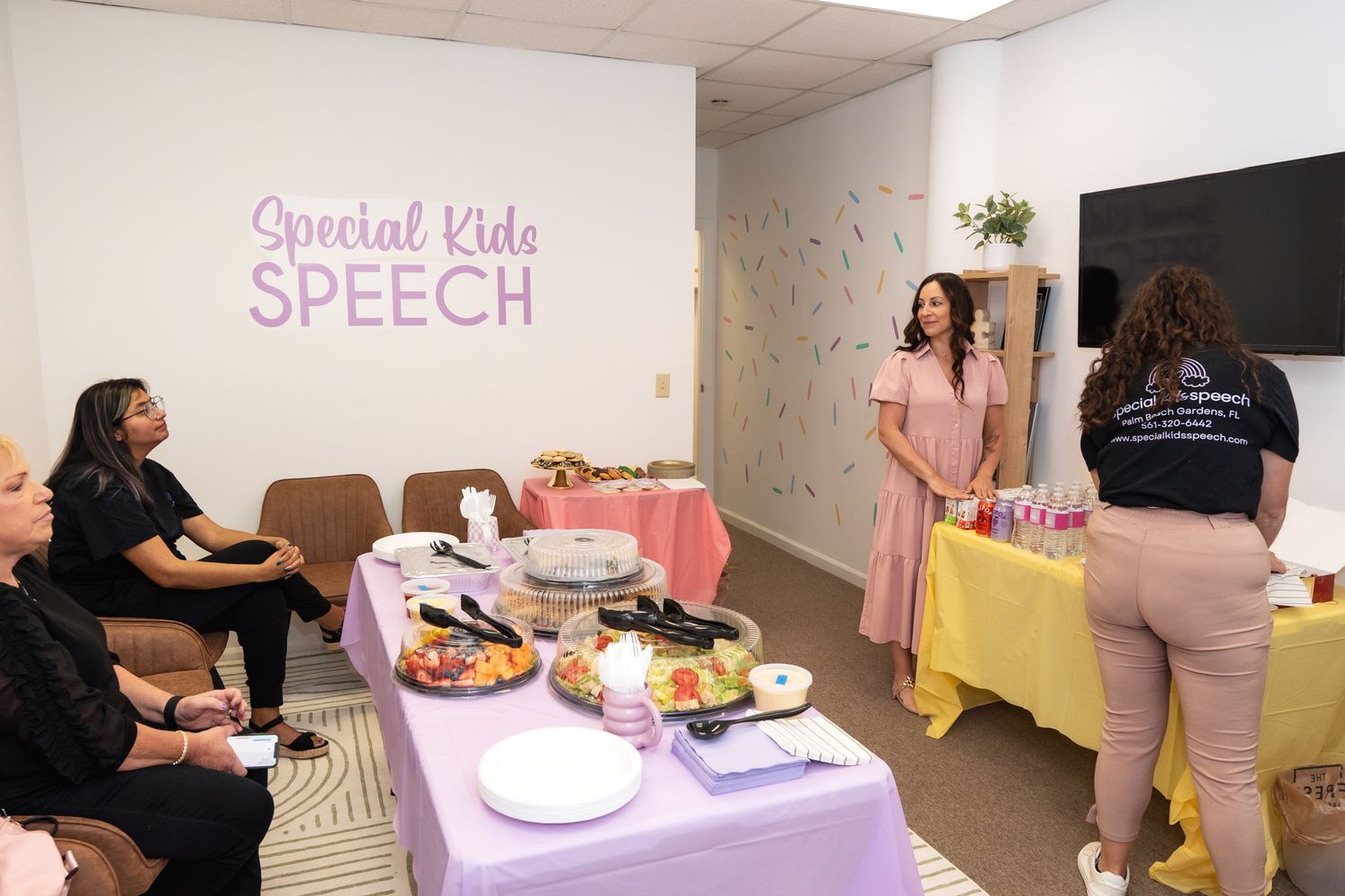 A meeting room setup with a purple banner reading 'Special Kids Speech' and refreshment table.