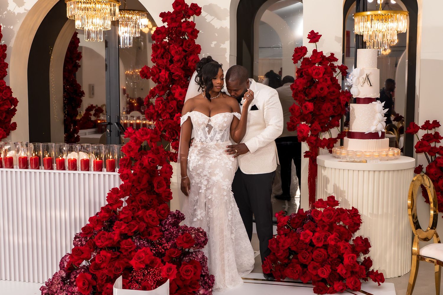 A wedding ceremony venue decorated with dramatic red rose arrangements and white accents throughout the space.