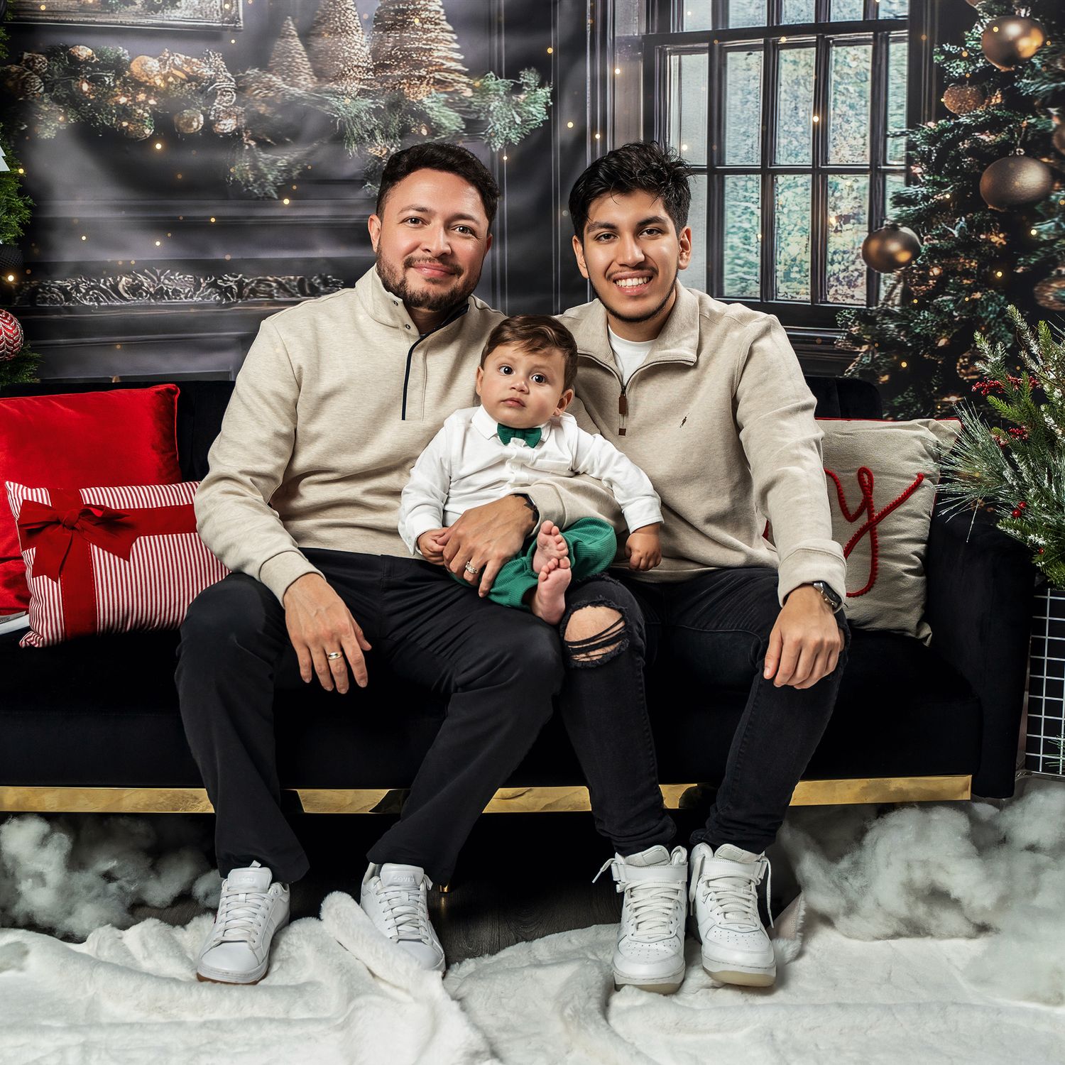 Three people sitting on bench with holiday decorations and Christmas tree in background.