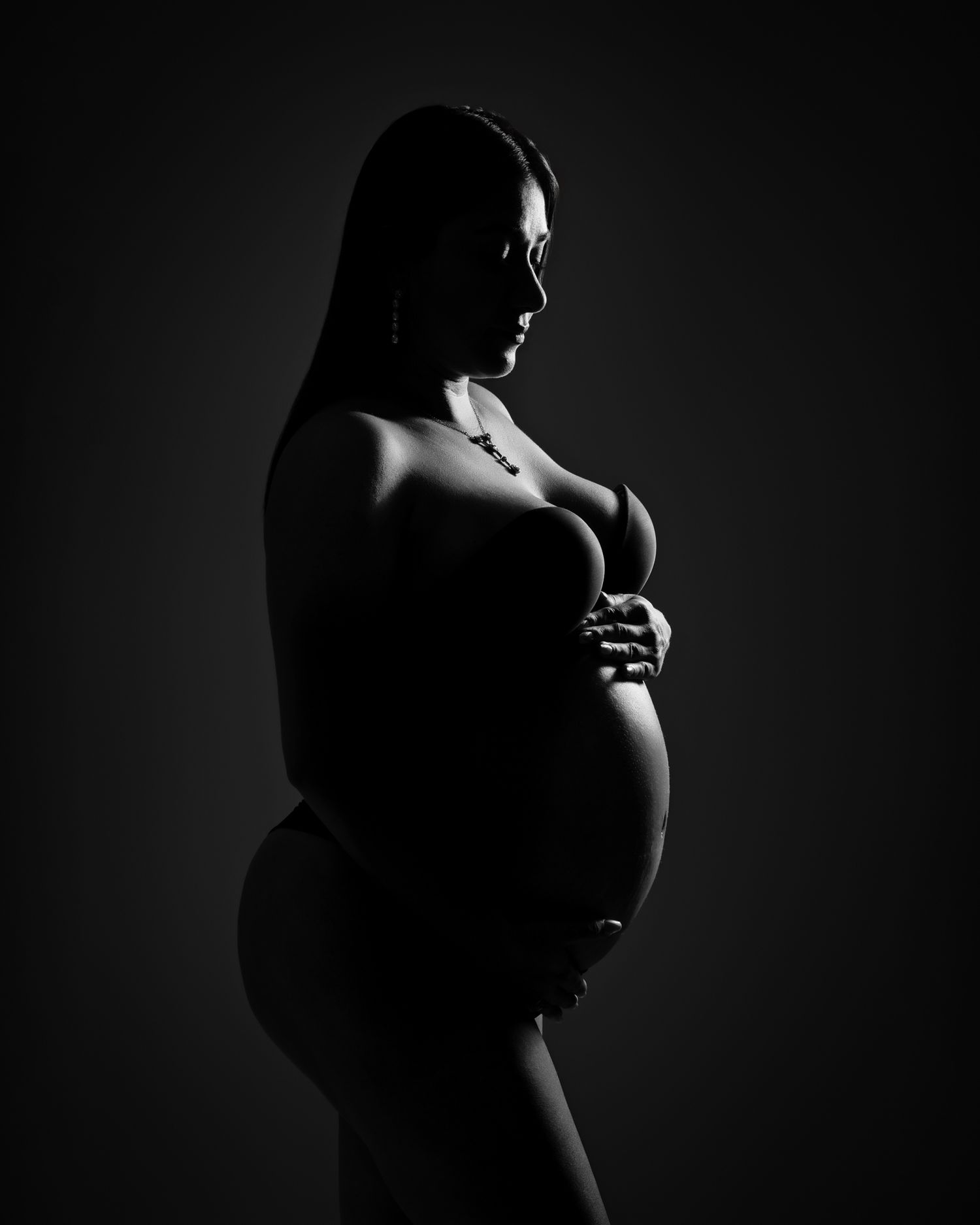 Dramatic black and white silhouette of expectant figure highlighting pregnancy curves.