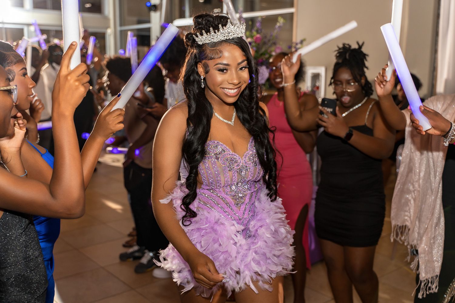 A celebratory scene at a formal event with people dancing and holding light sticks in a festive atmosphere.