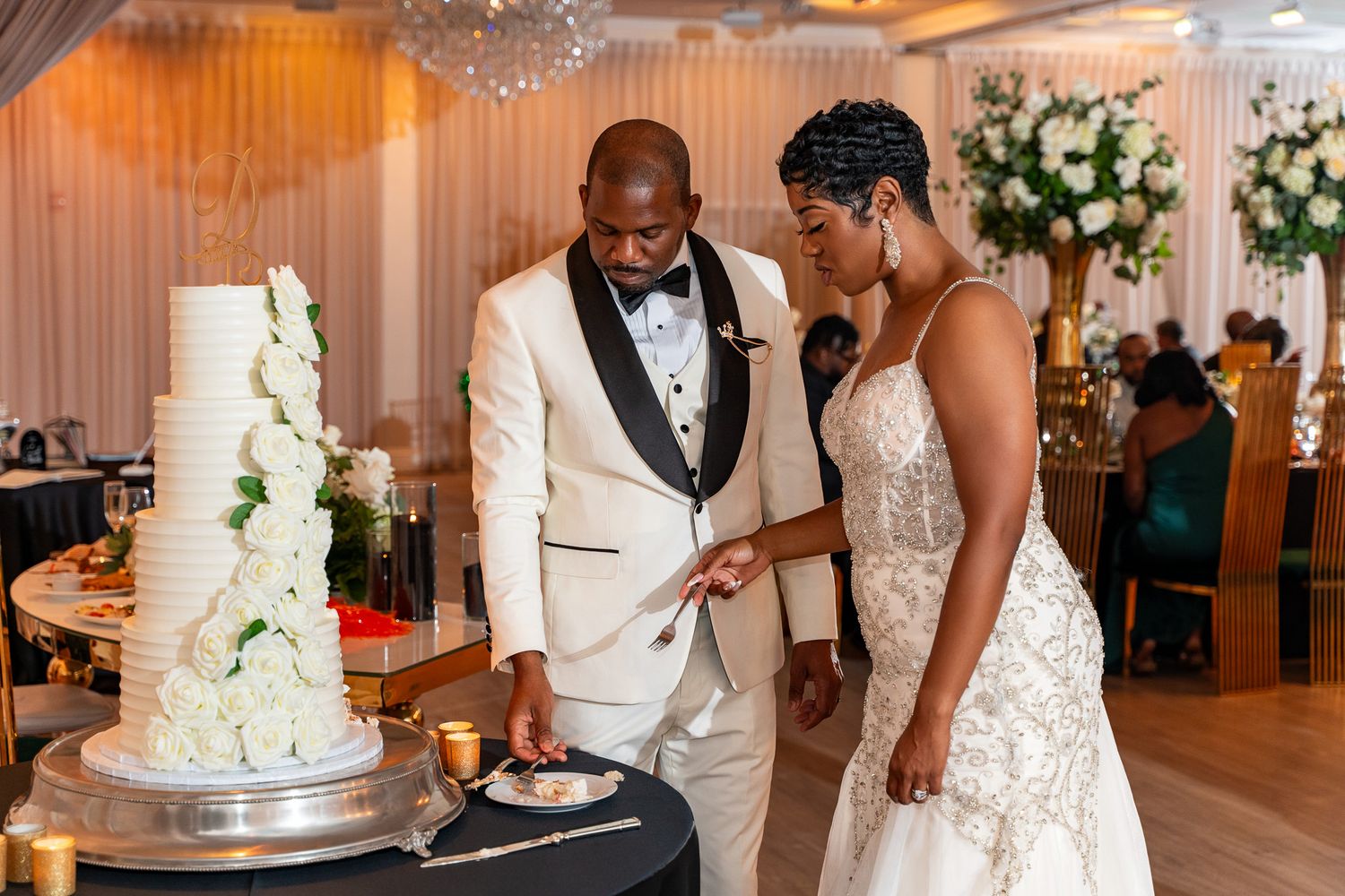 Couple cuts their elegant white wedding cake in a beautifully decorated reception venue.
