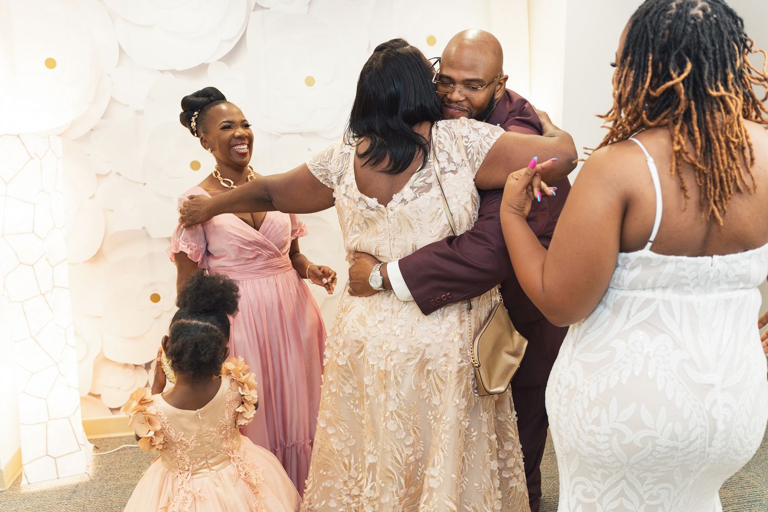 Candid moment of wedding celebration with guests laughing and embracing in formal attire.
