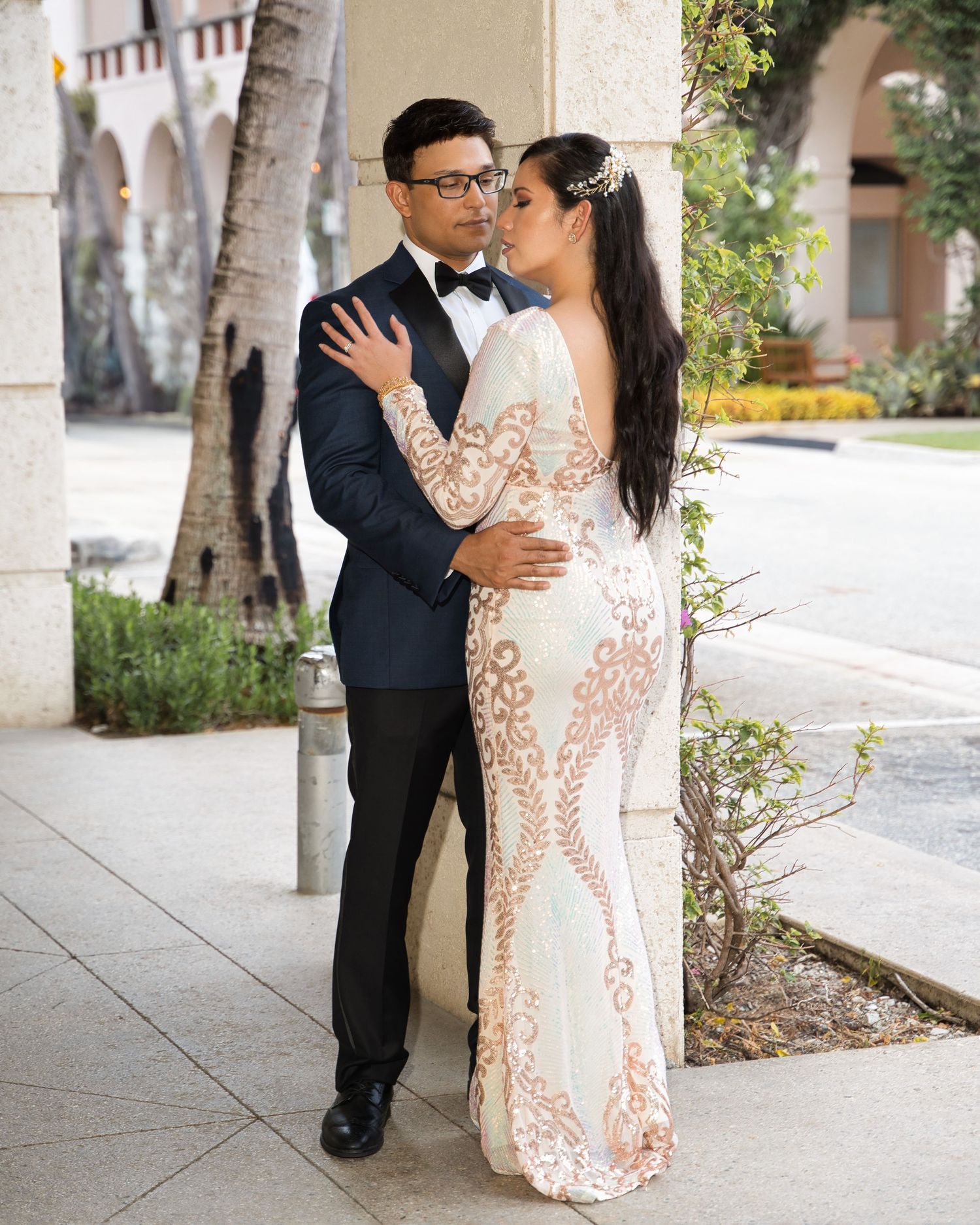 Romantic wedding portrait under arched colonnade with palm trees.