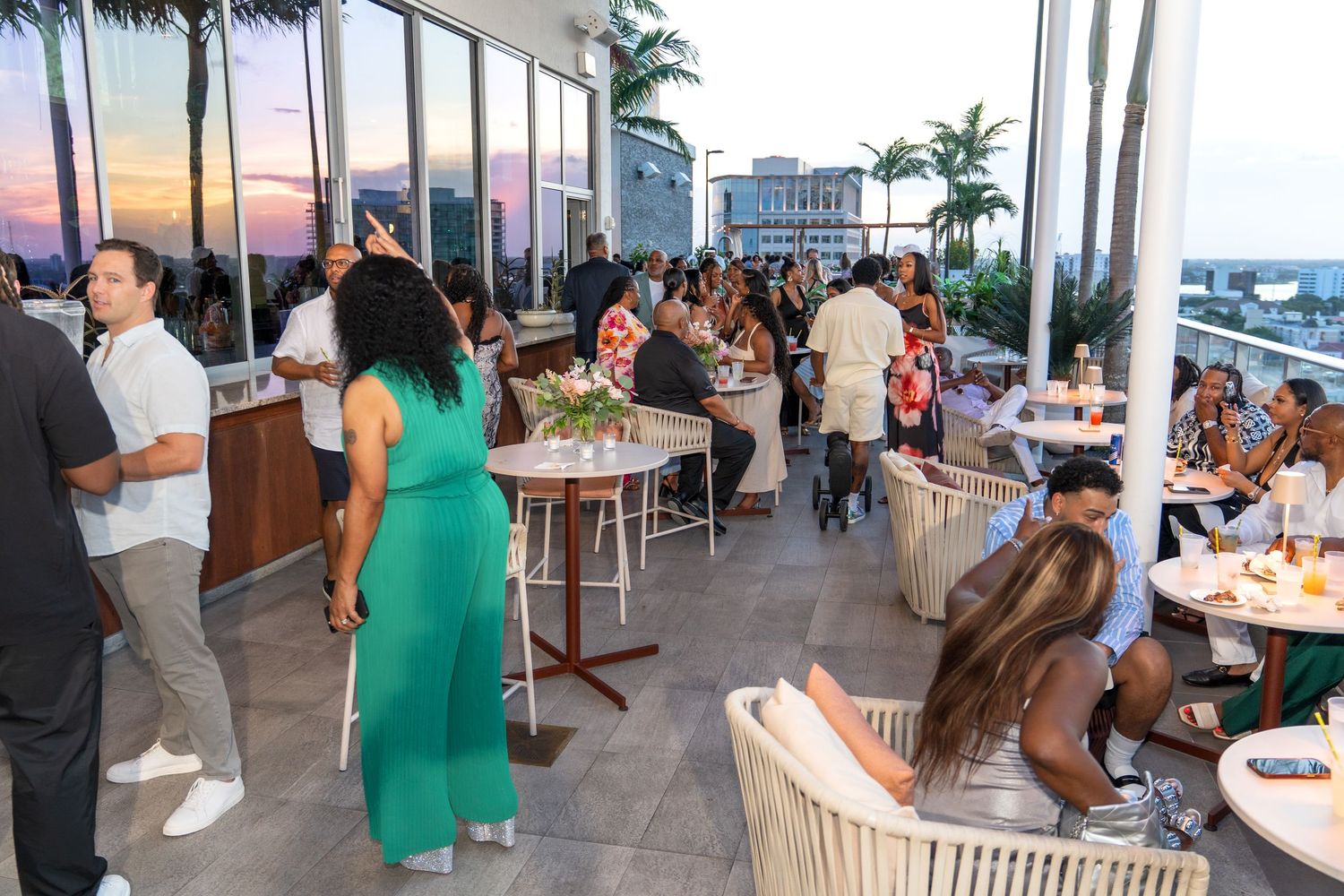 Guests enjoying a waterfront party venue with palm trees and ocean views at sunset.