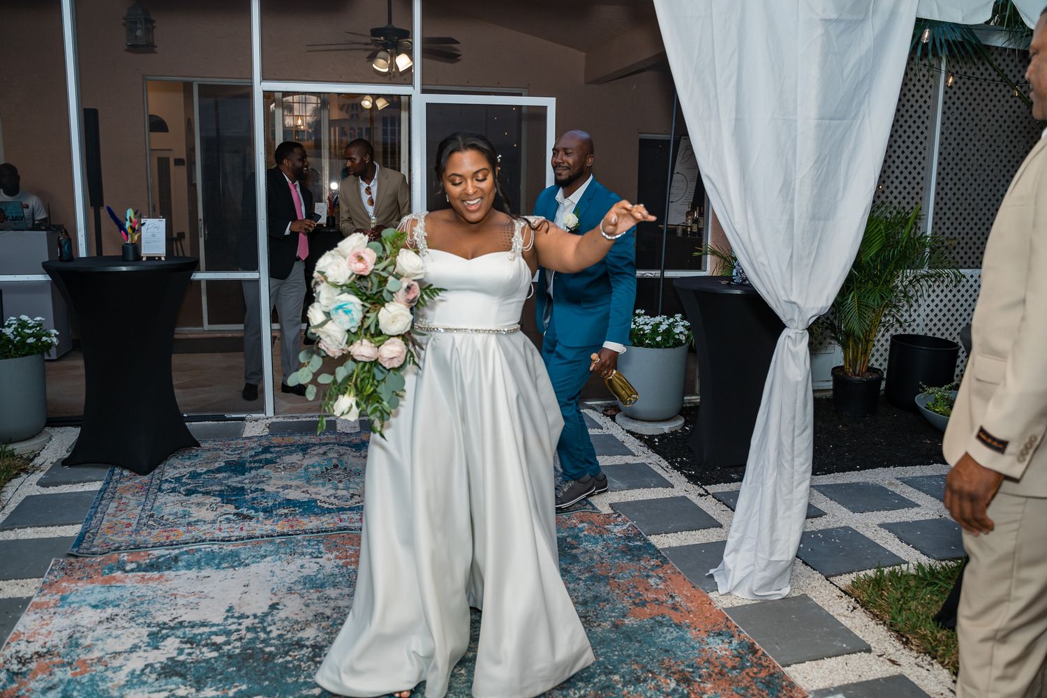 Bride in elegant white gown dances joyfully at outdoor wedding reception.