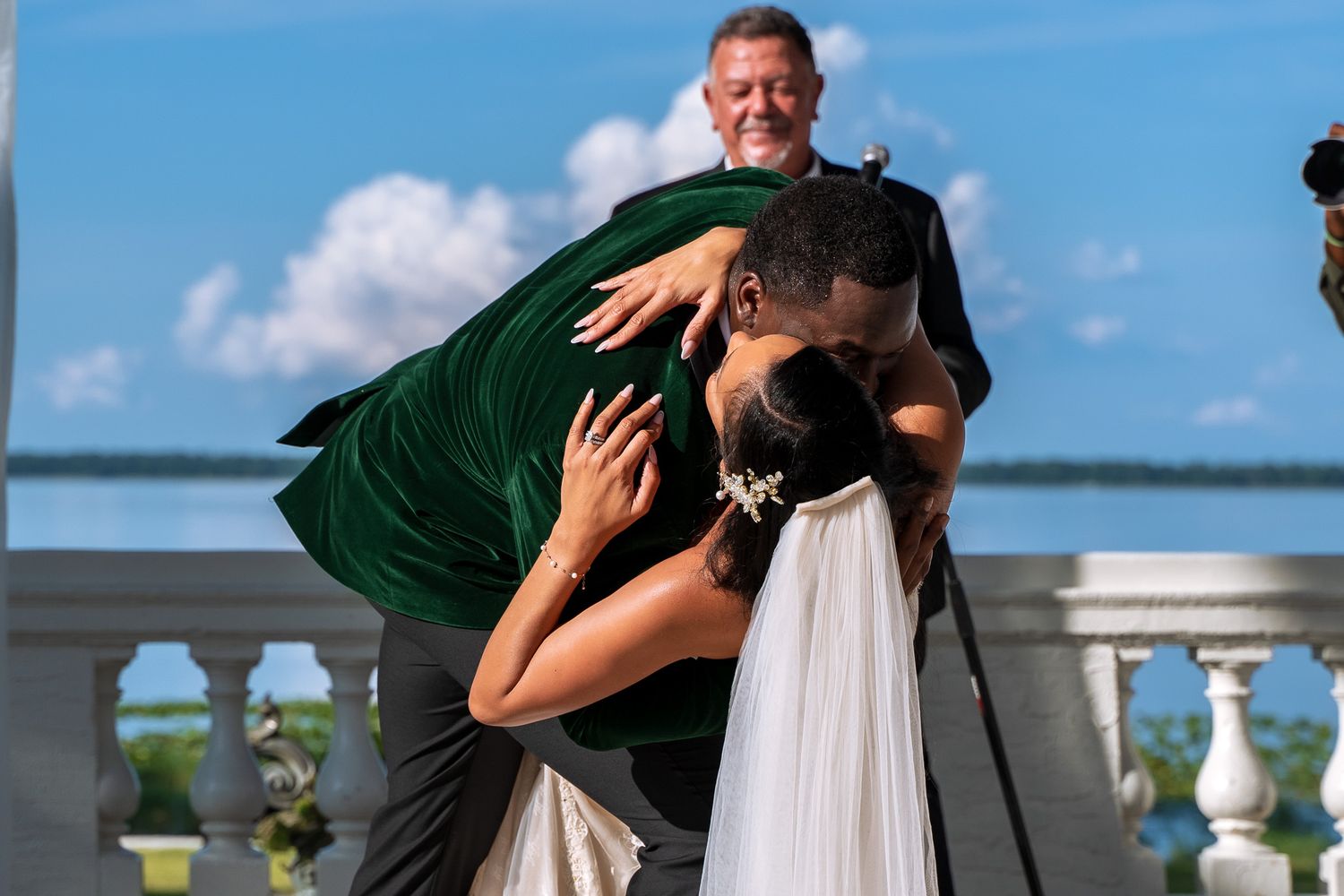 A romantic kiss between newlyweds at their outdoor waterfront ceremony.