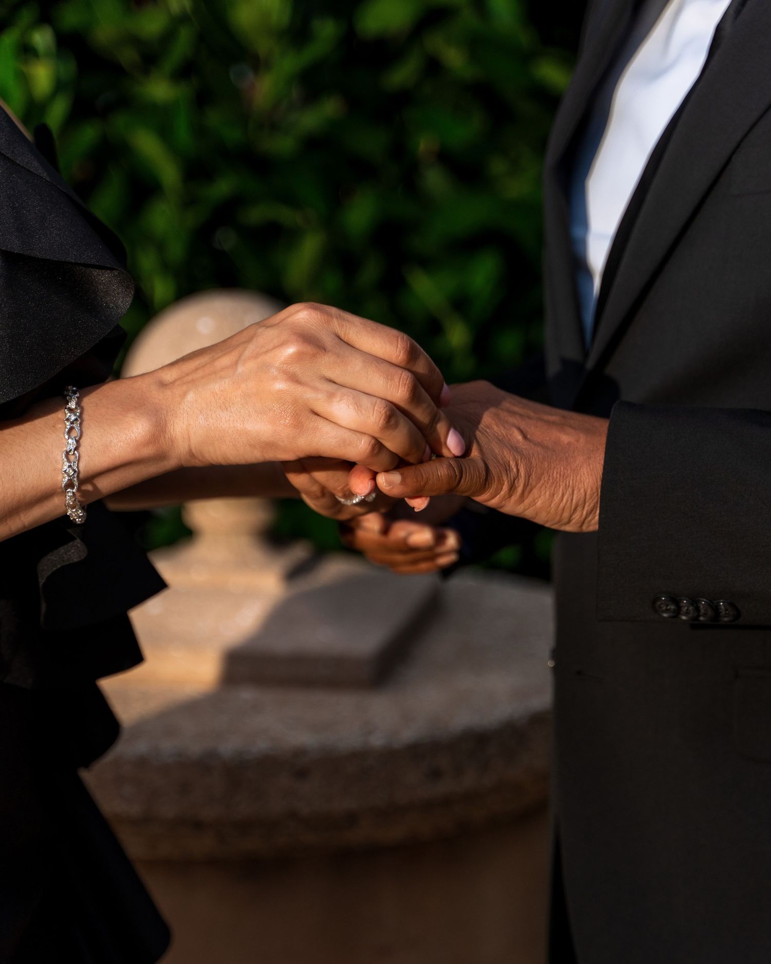 Close-up of hands exchanging rings during an intimate outdoor ceremony.