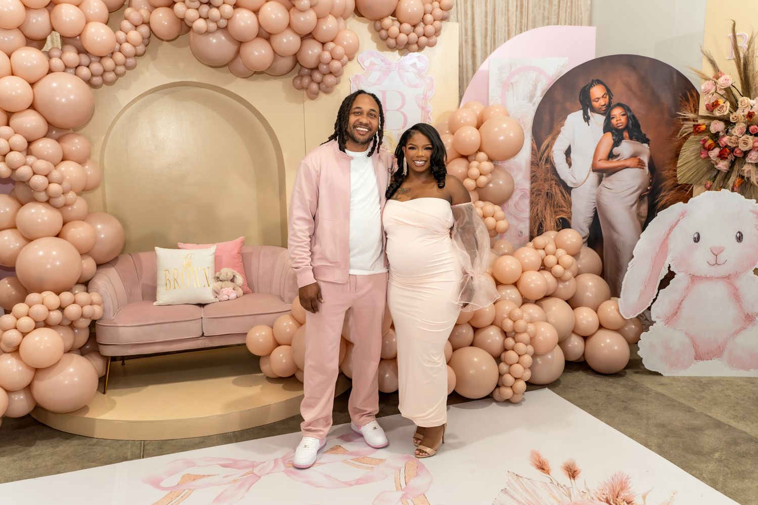 Baby shower celebration with pink balloon arch and bunny decorations.