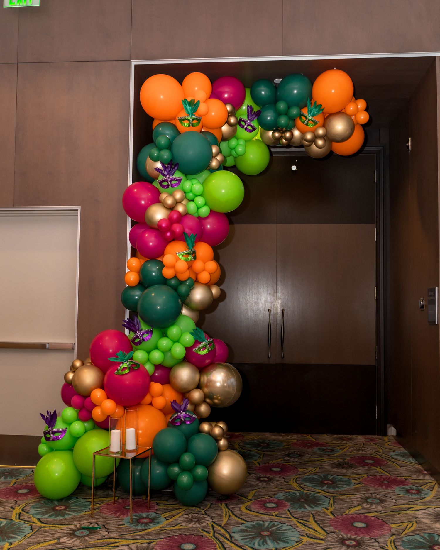 Colorful balloon arch installation with orange, green, pink and gold balloons creating a festive entrance display.