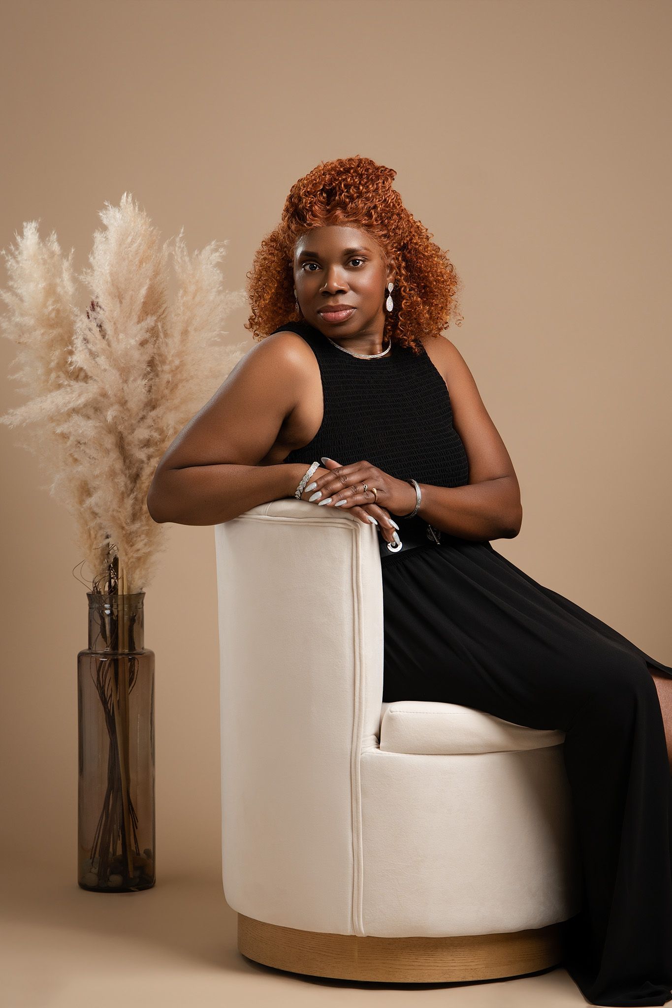 Elegant studio portrait with a black dress against neutral backdrop with pampas grass decor.