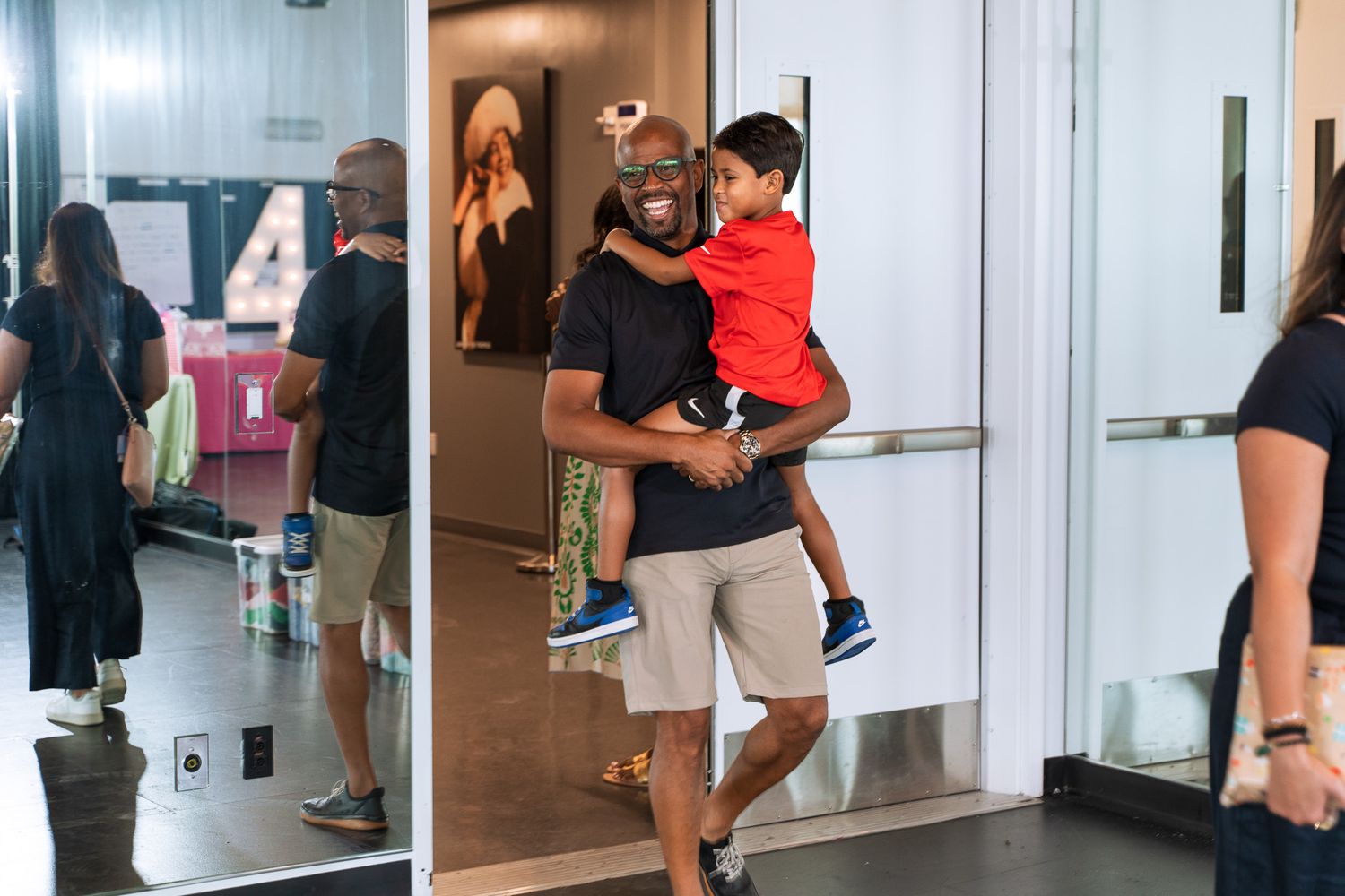 People gathering in a studio or event space with children and adults mingling in casual attire.