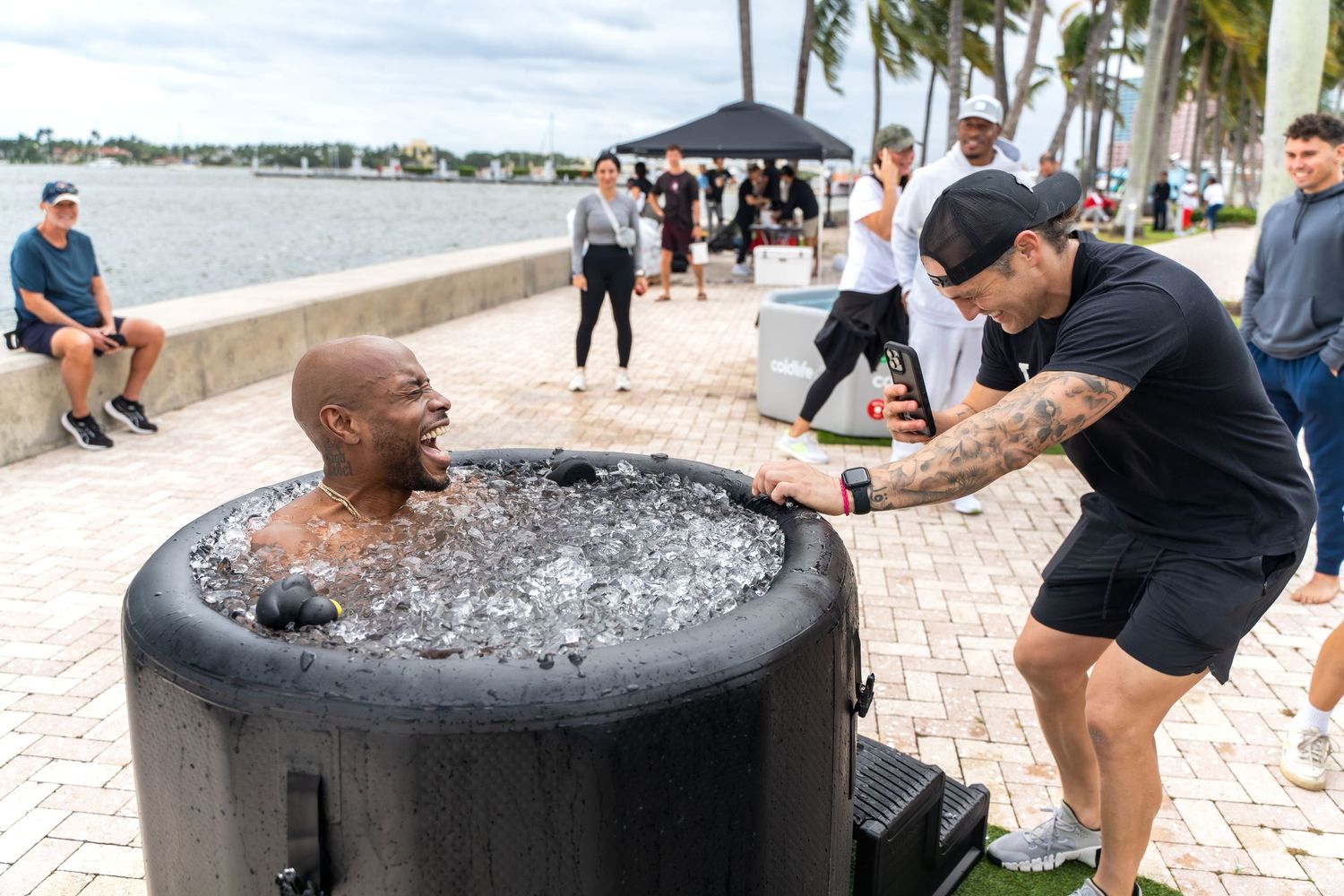 Two people interacting at an outdoor ice bath station during a wellness event.