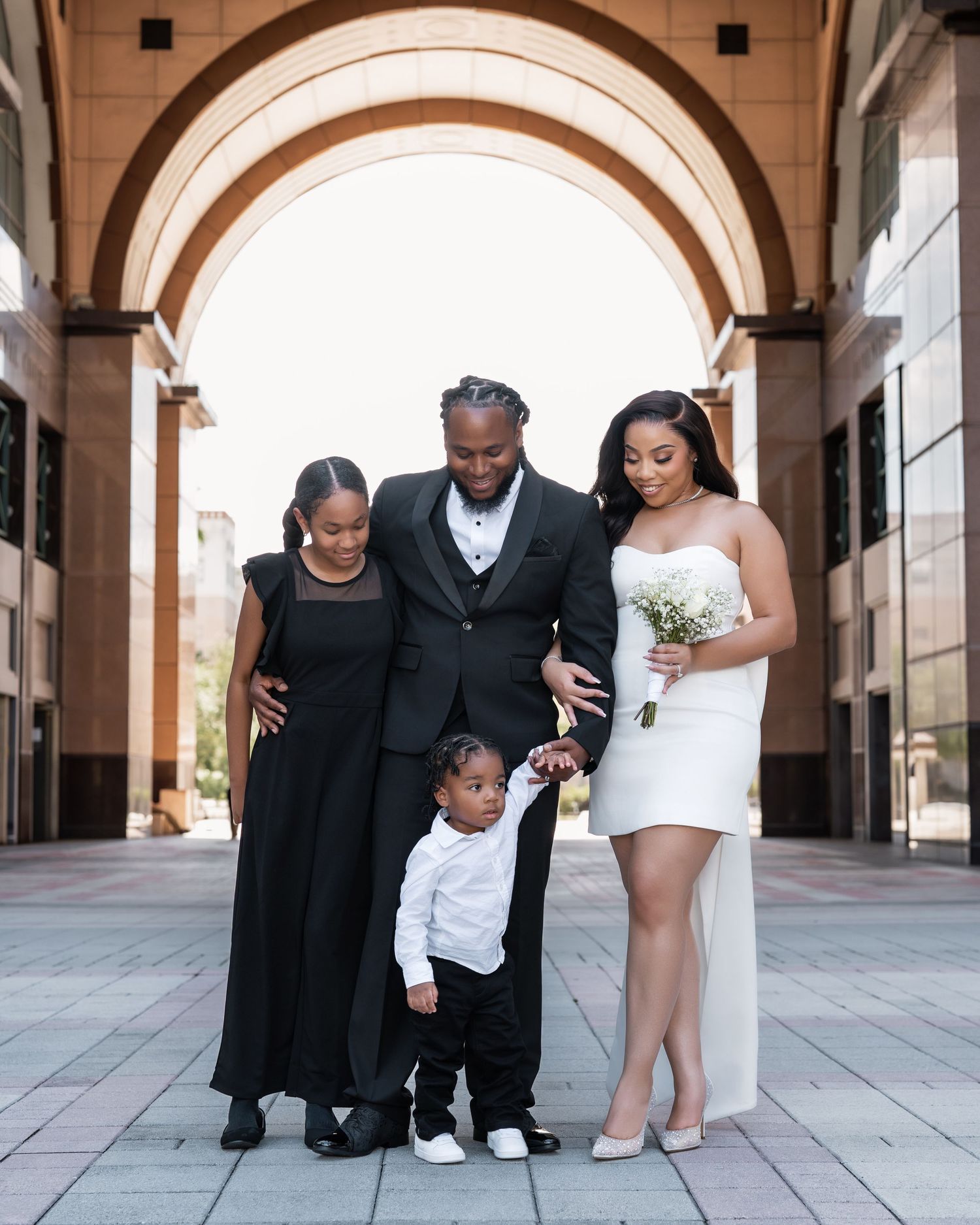 A family poses together under elegant stone archways during a formal celebration.